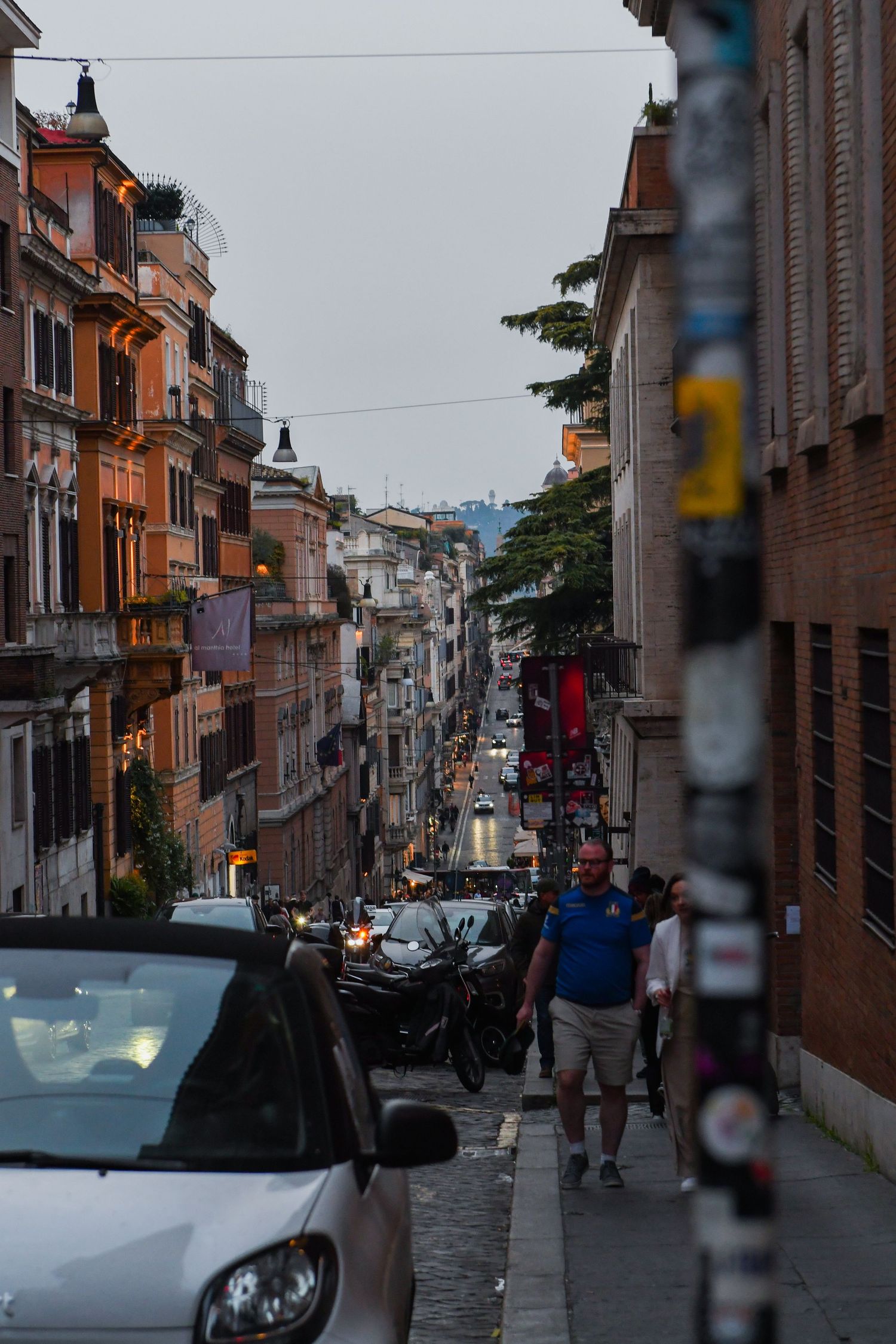 Narrow European street with brick buildings and parked cars in an urban neighborhood.