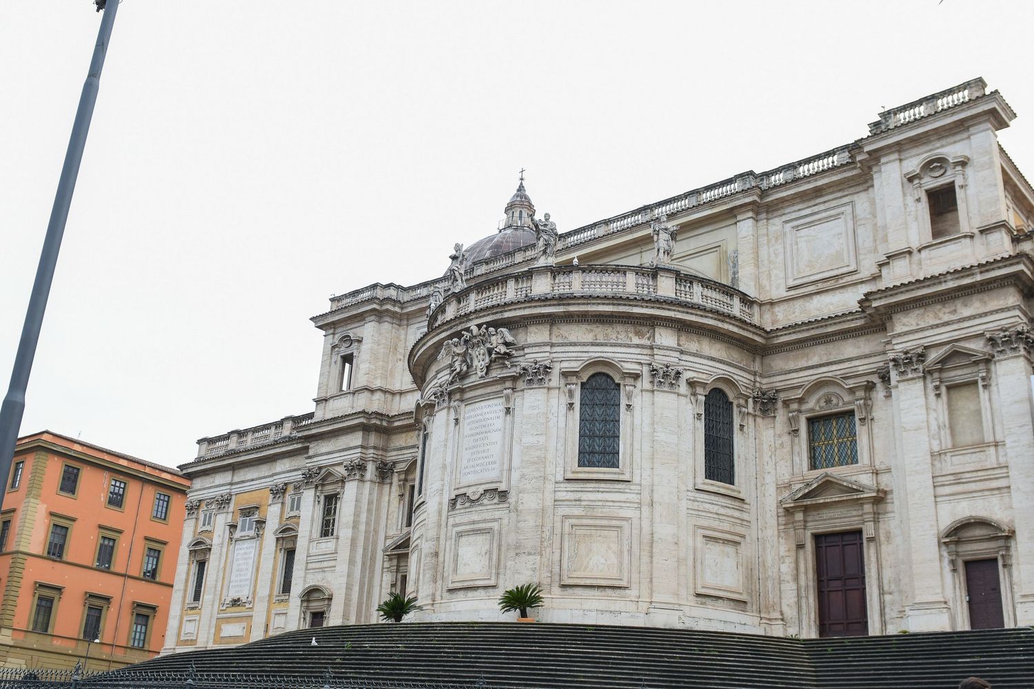 Exterior view of a grand Baroque church with curved white stone facade and ornate architectural details in Rome.