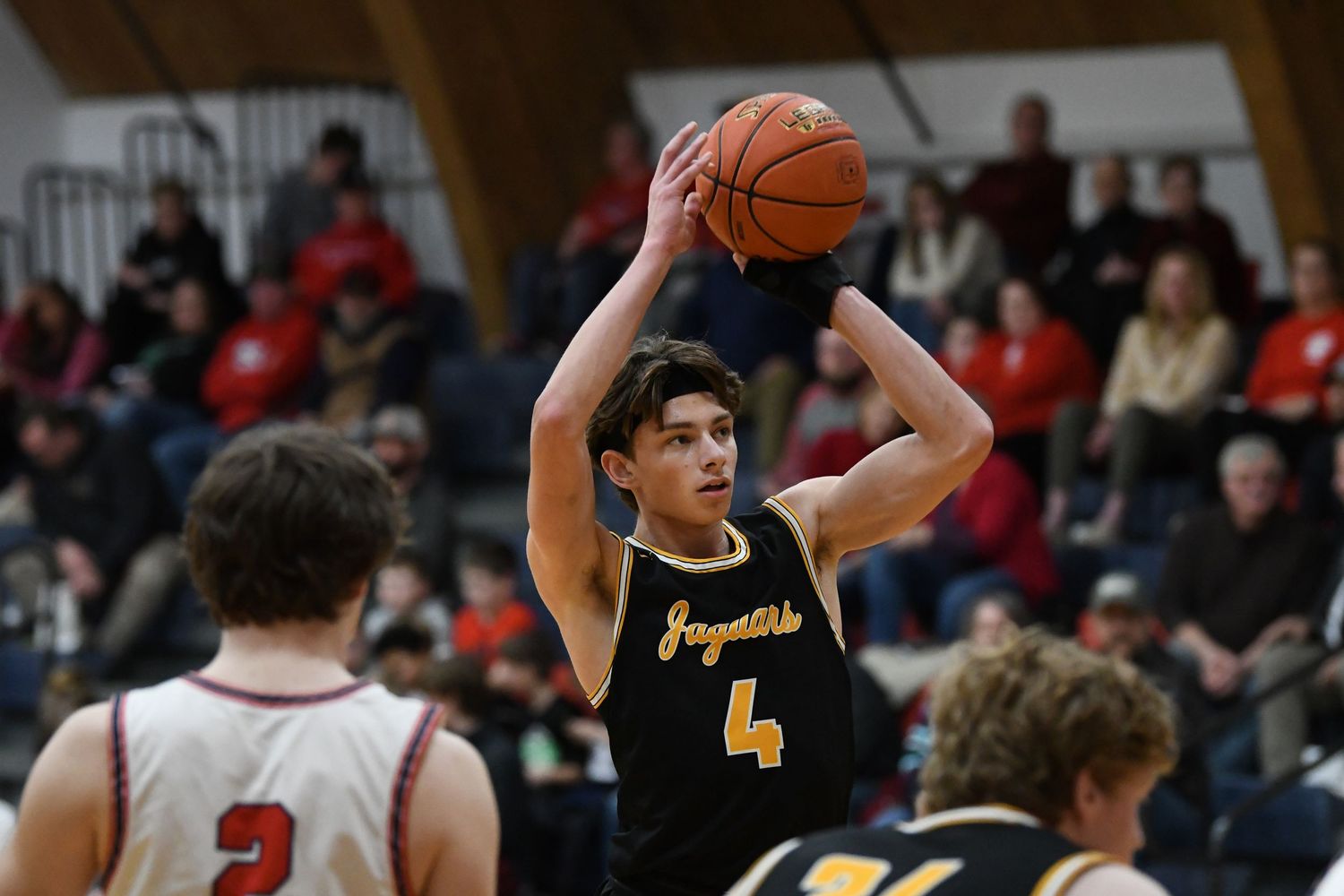 Player in black jersey number 4 prepares to shoot basketball during game.