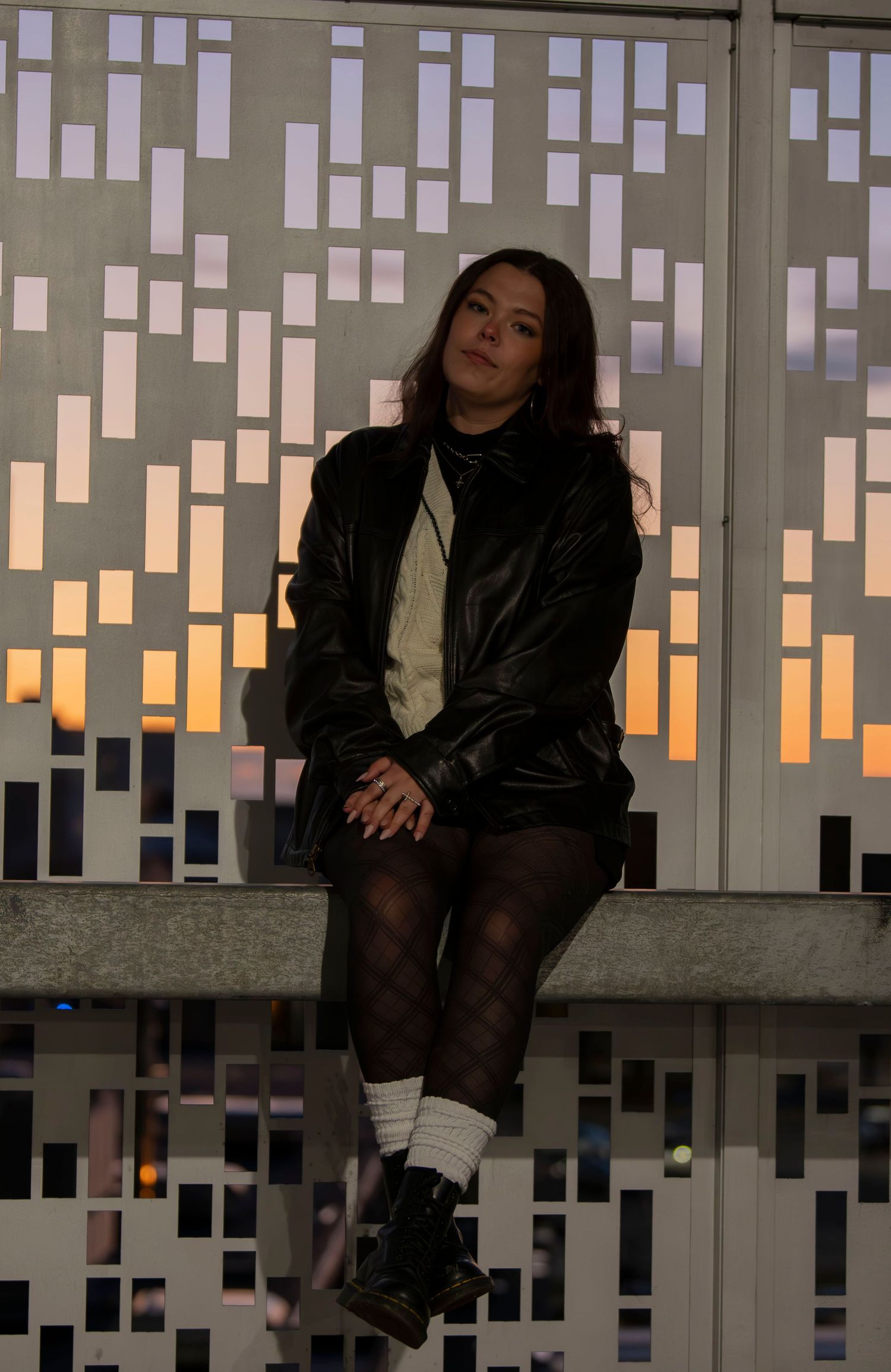 A moody portrait against a geometric wall with sunset lighting filtering through.