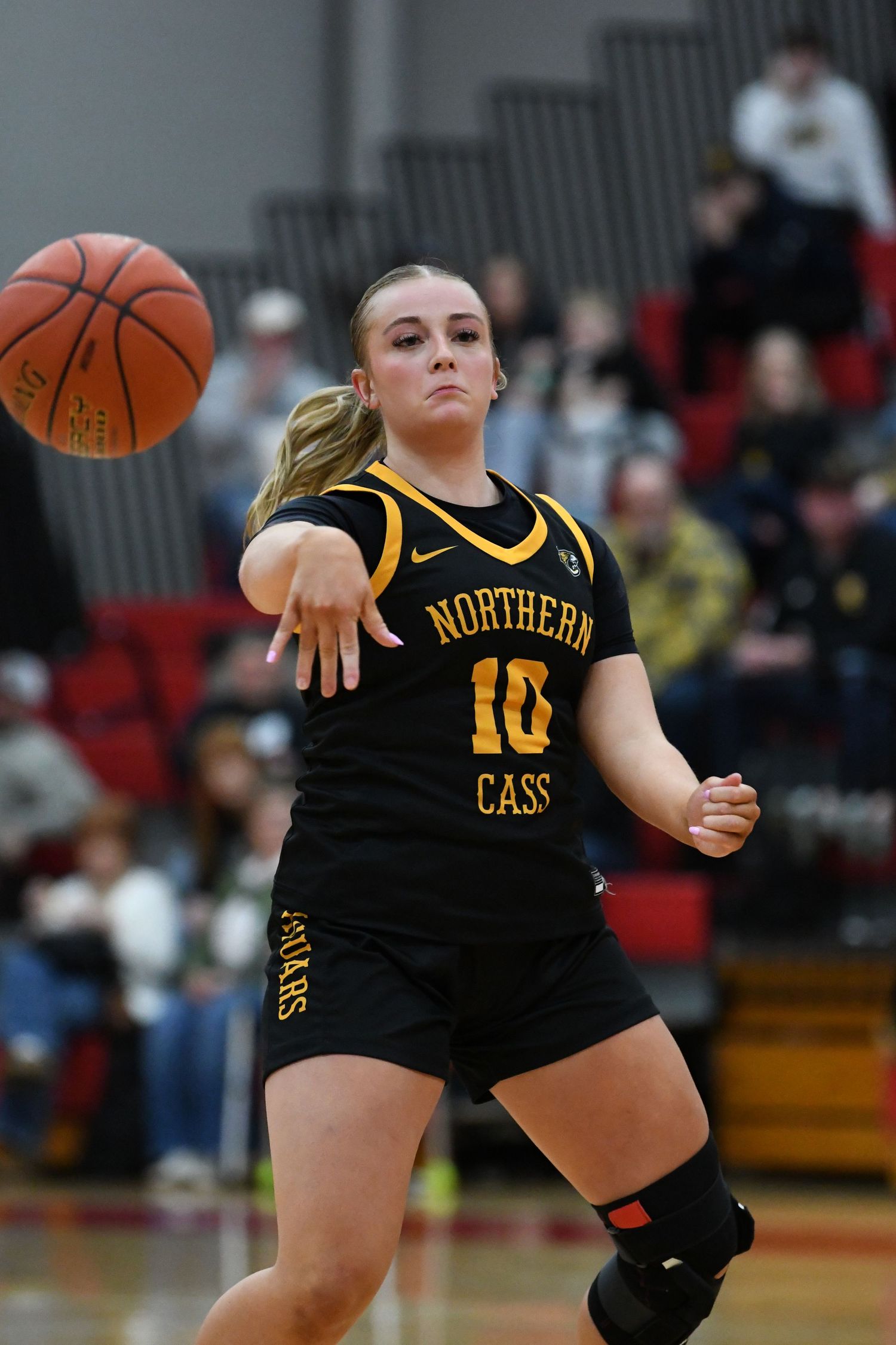 Player in black Northern Cass uniform passes basketball during competitive game.