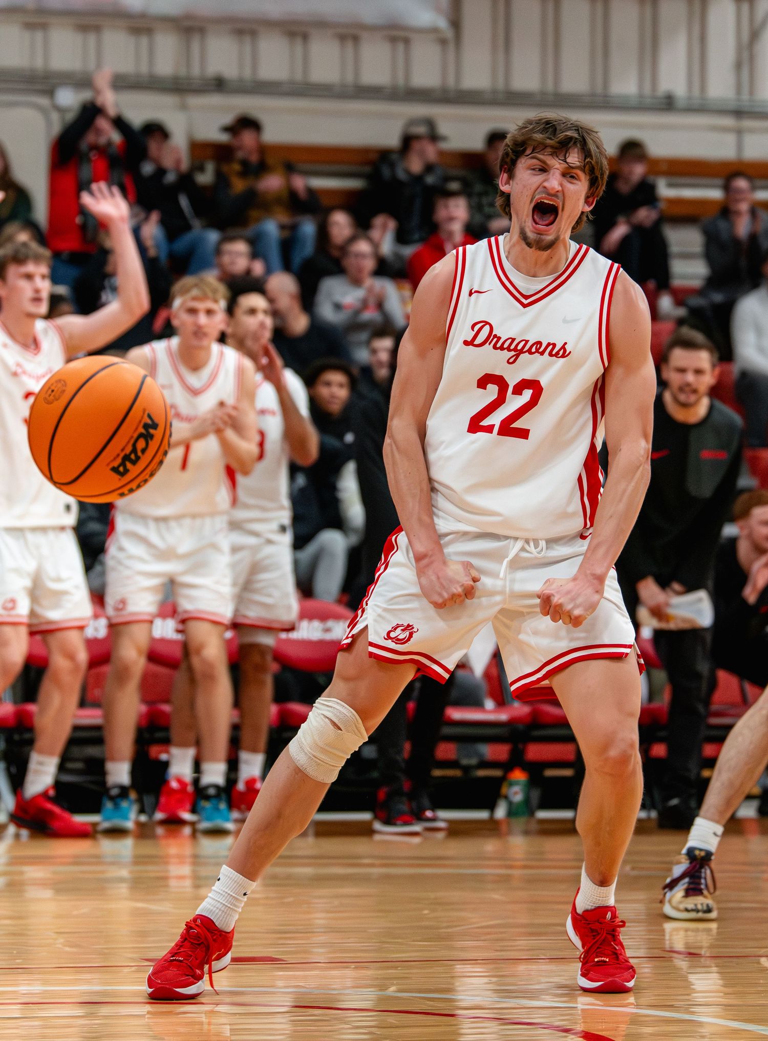 Basketball players in red and white uniforms compete on a hardwood court during an intense game.