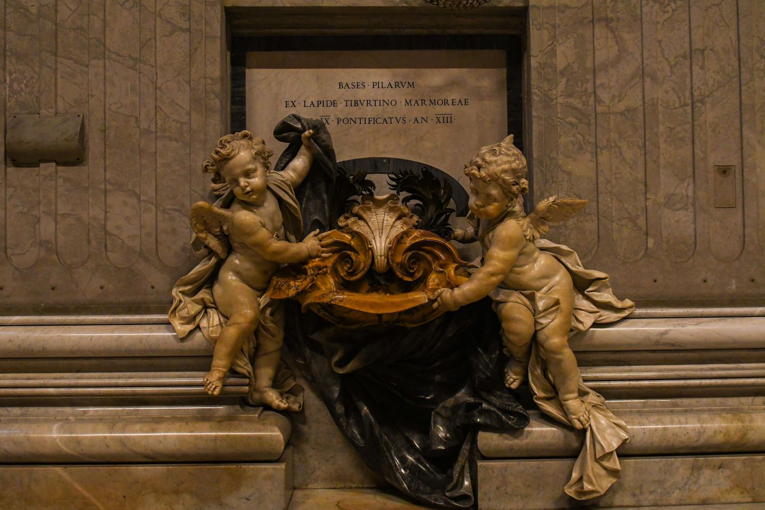 Ornate golden cherub sculptures adorning a marble wall in classical baroque style.
