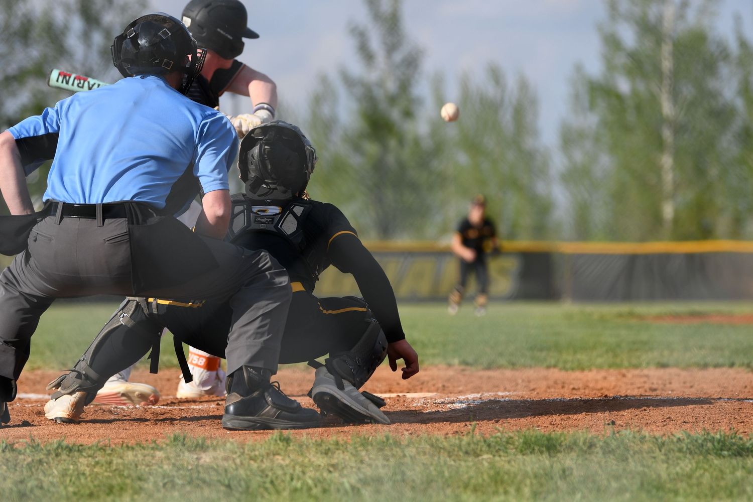 Baseball umpire and catcher watch closely at home plate during a game.