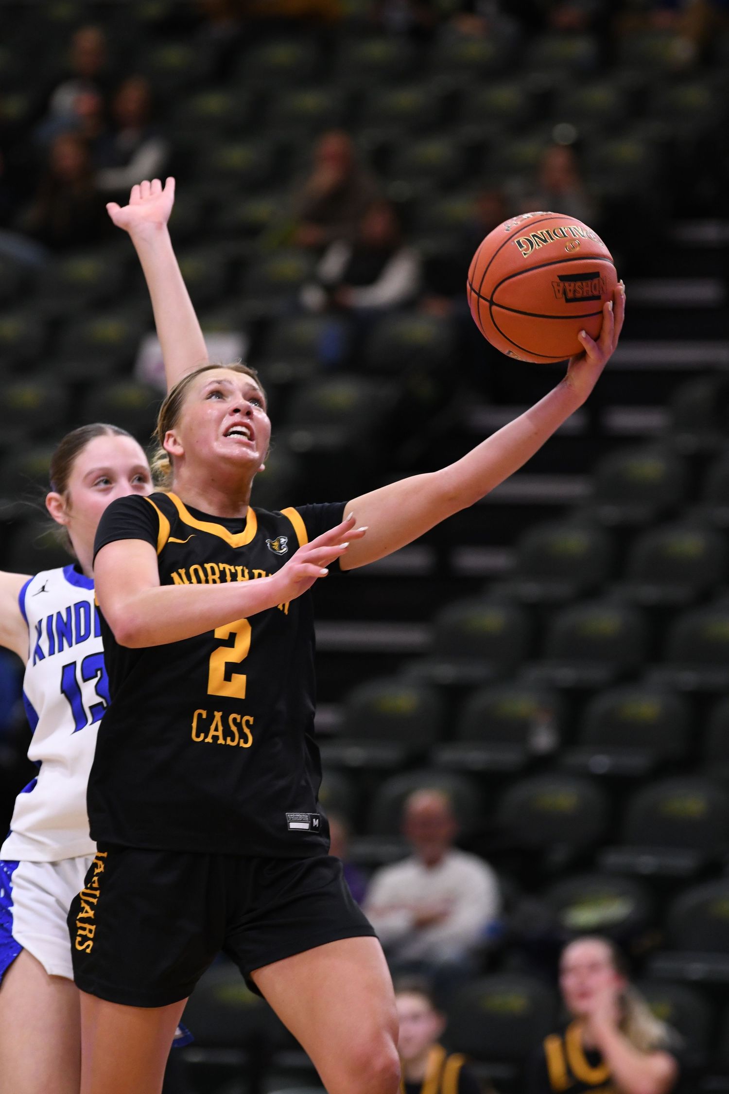 Player in black Northern Cass uniform makes layup during basketball game.