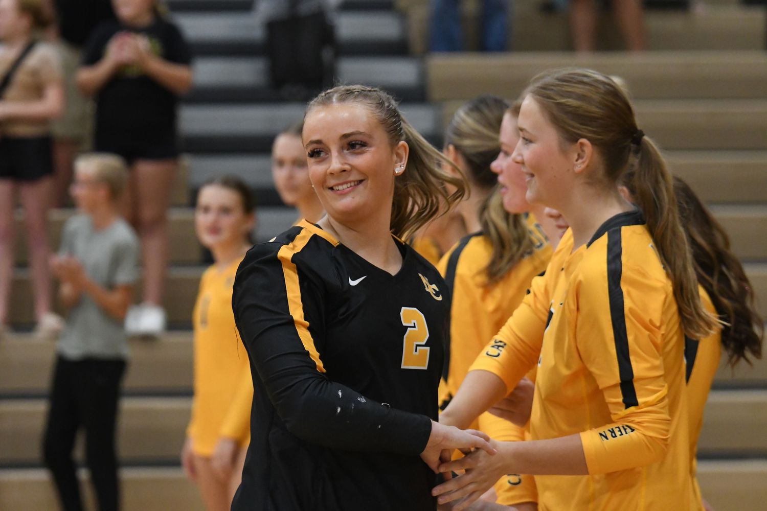 Players in black and yellow uniforms share a happy moment on the sideline.