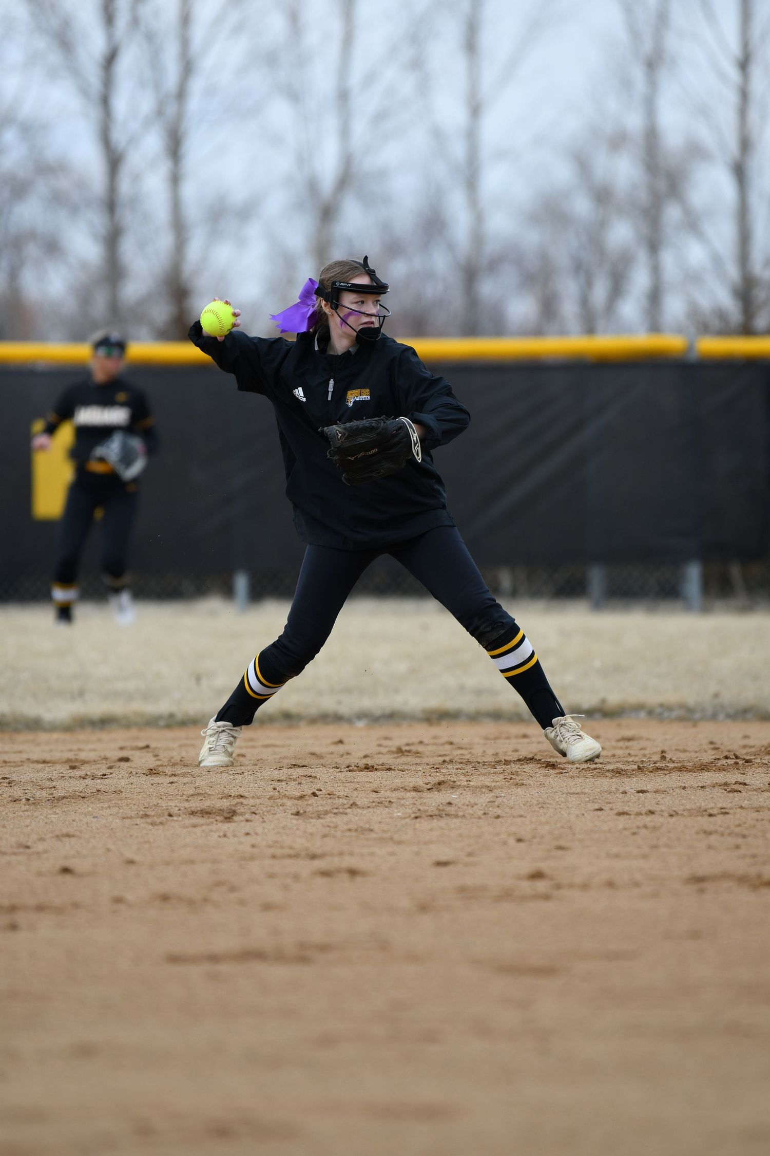 Softball player makes diving catch attempt on dirt infield.