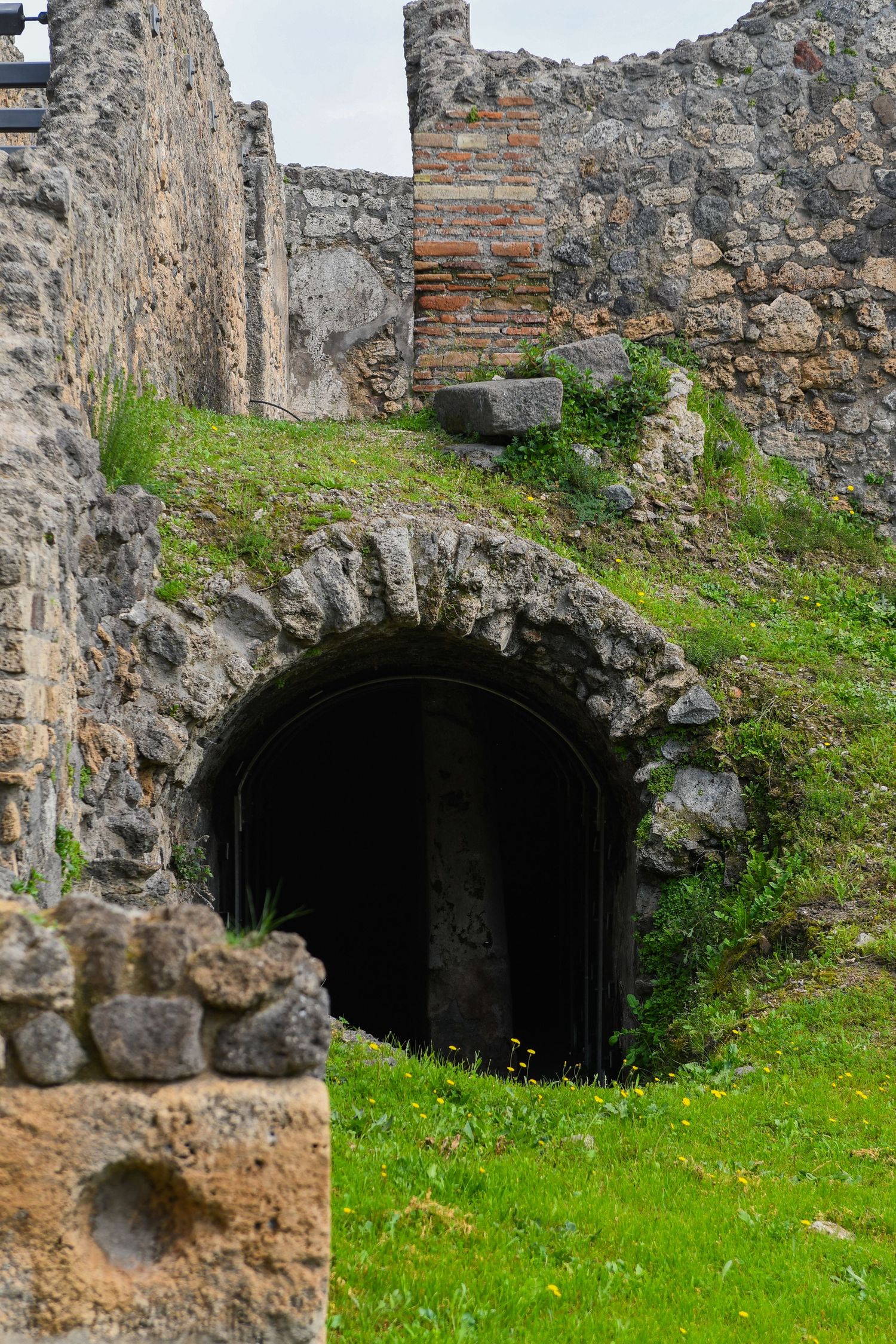 Stone archways built into a grassy hillside form mysterious entrances to underground chambers or tunnels.