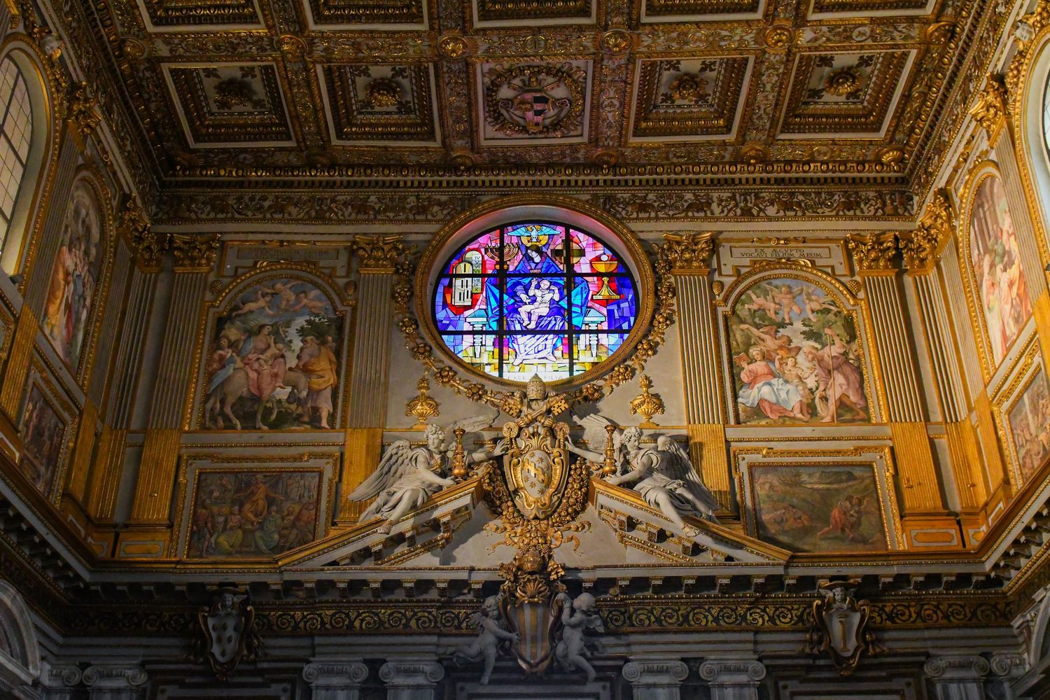 Ornate ceiling with gilded details and stained glass window in an Italian baroque church interior.