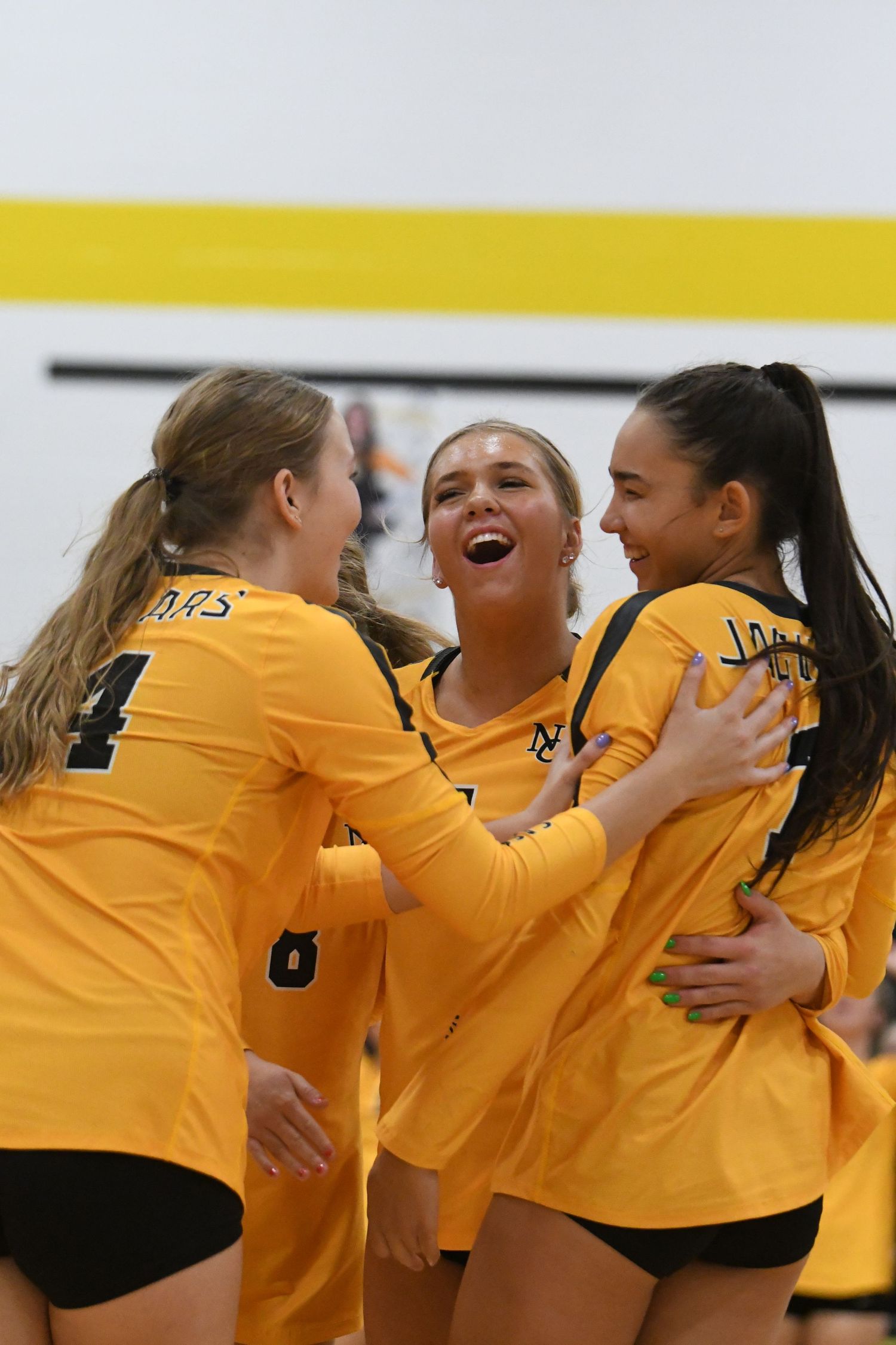 Team players in yellow jerseys celebrate together with excitement and joy after scoring a point.