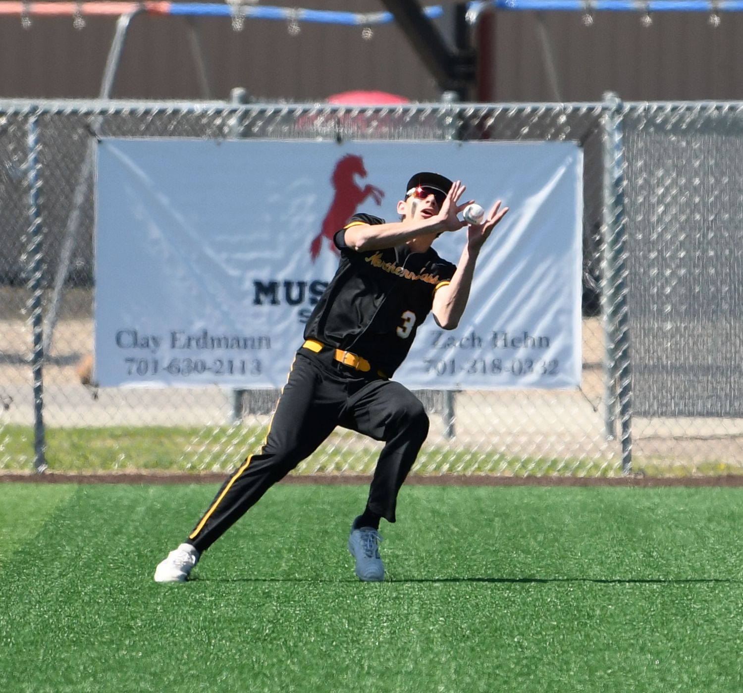 Baseball player in black uniform makes a diving catch attempt on the field during a game.