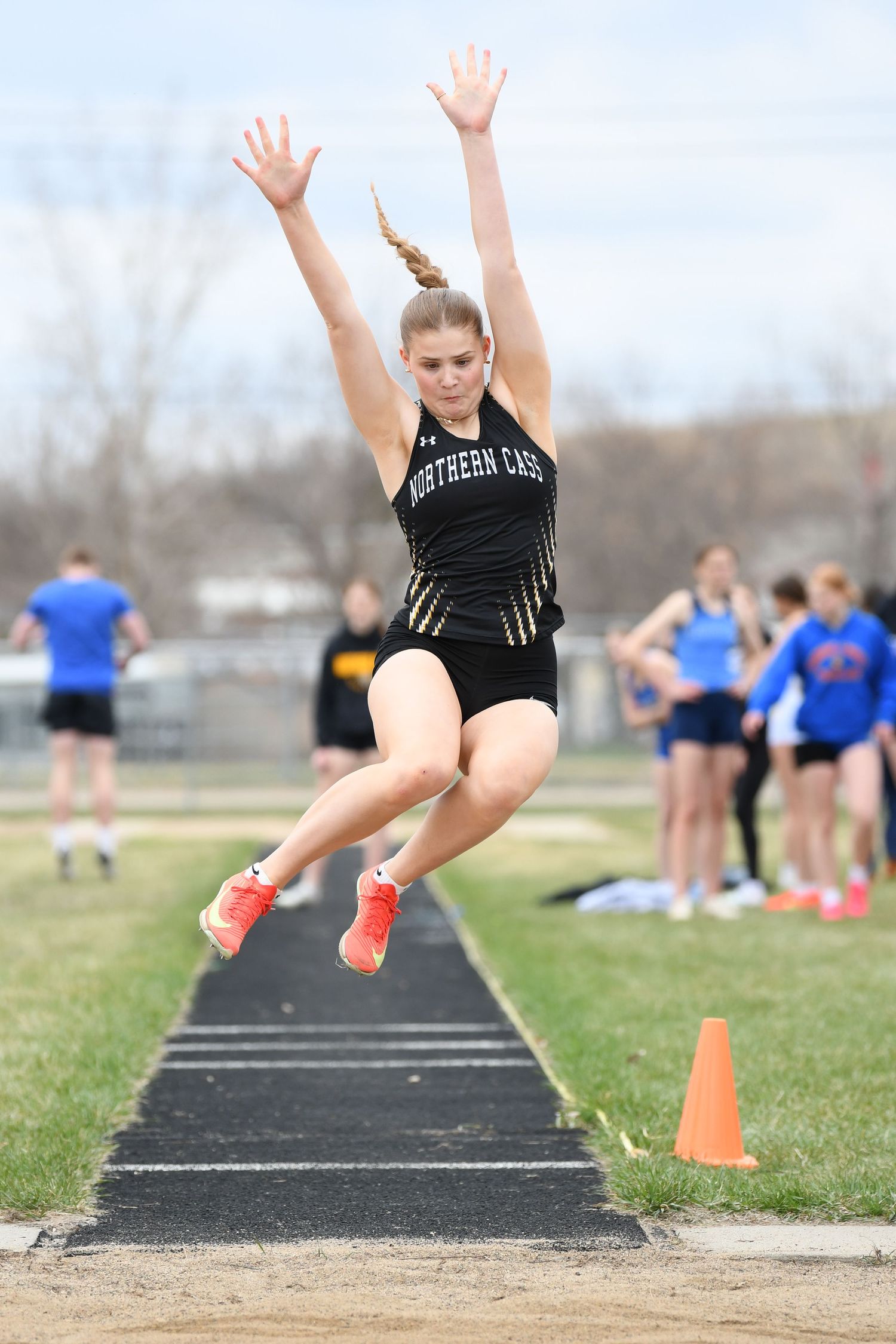 Athlete shows perfect form during long jump attempt on outdoor track.