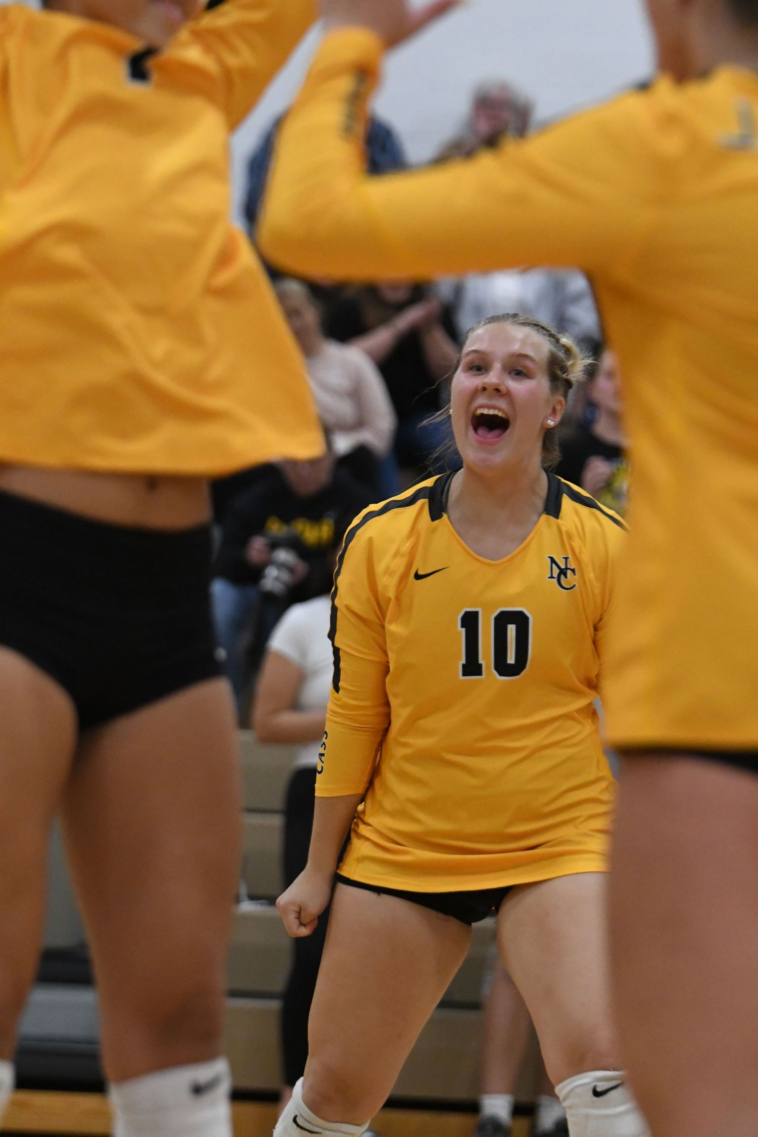 Volleyball player in yellow jersey celebrates enthusiastically during match.