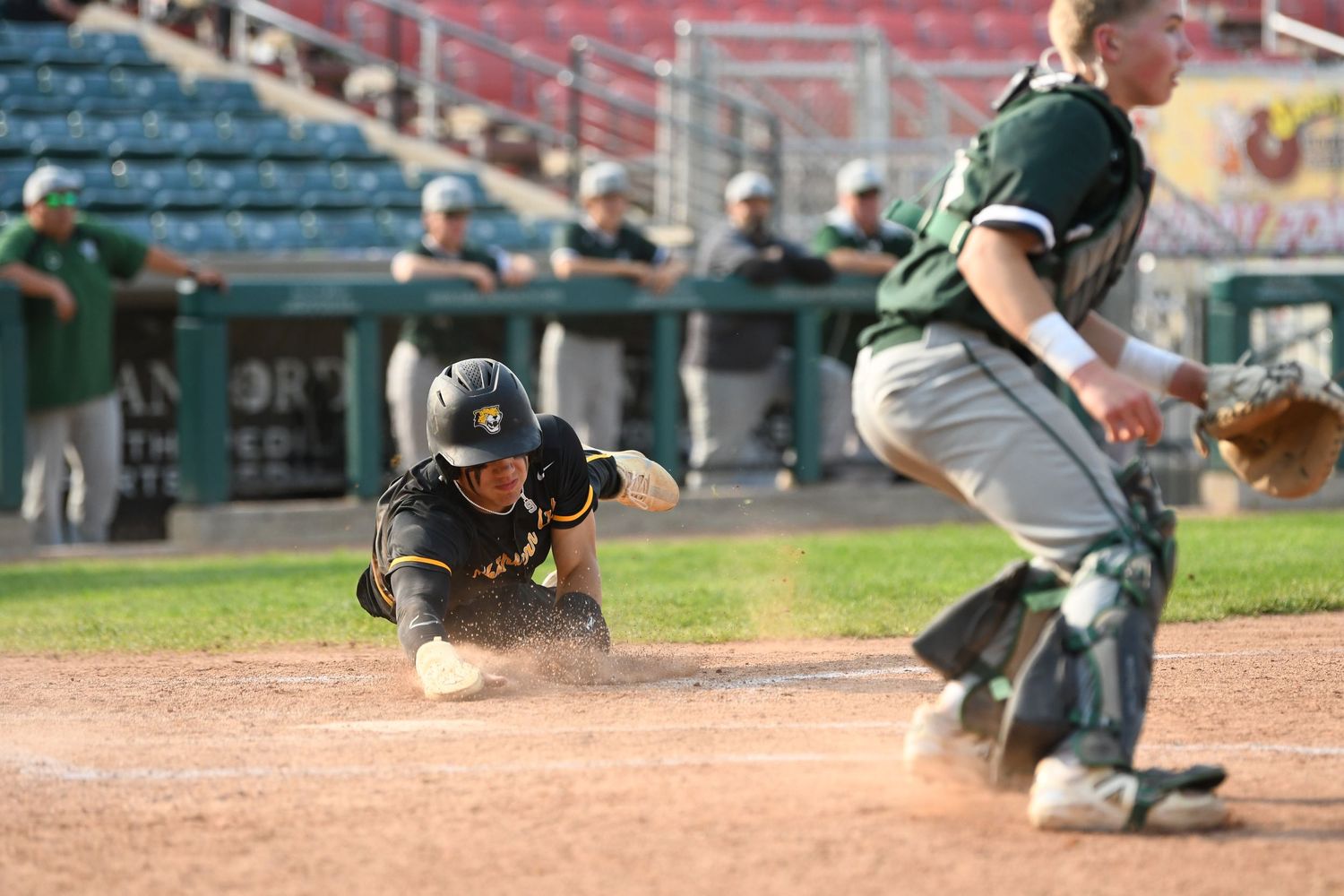 Baseball players executing sliding drills on the infield during team practice.