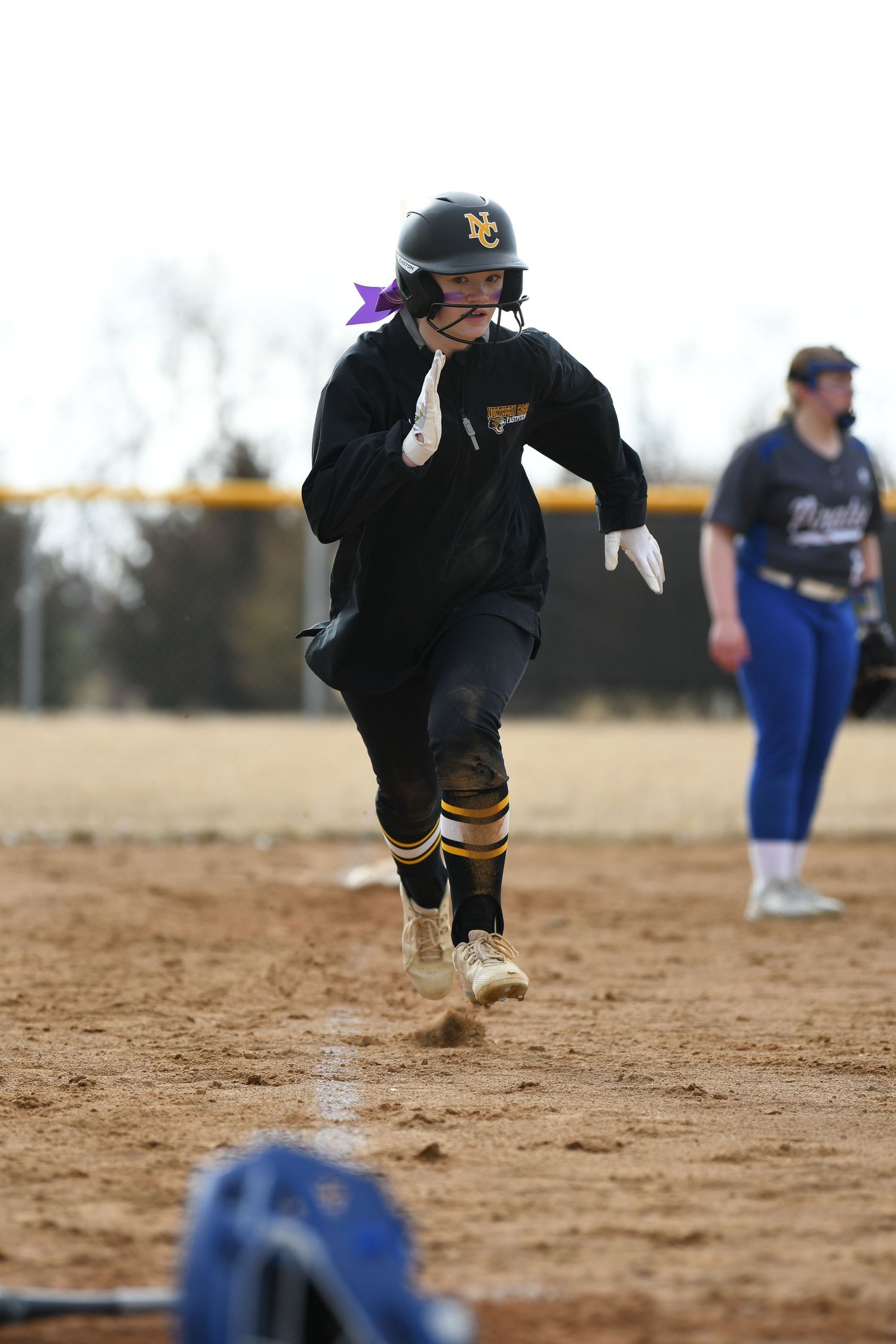Softball infielder charging forward to field a ground ball during game.