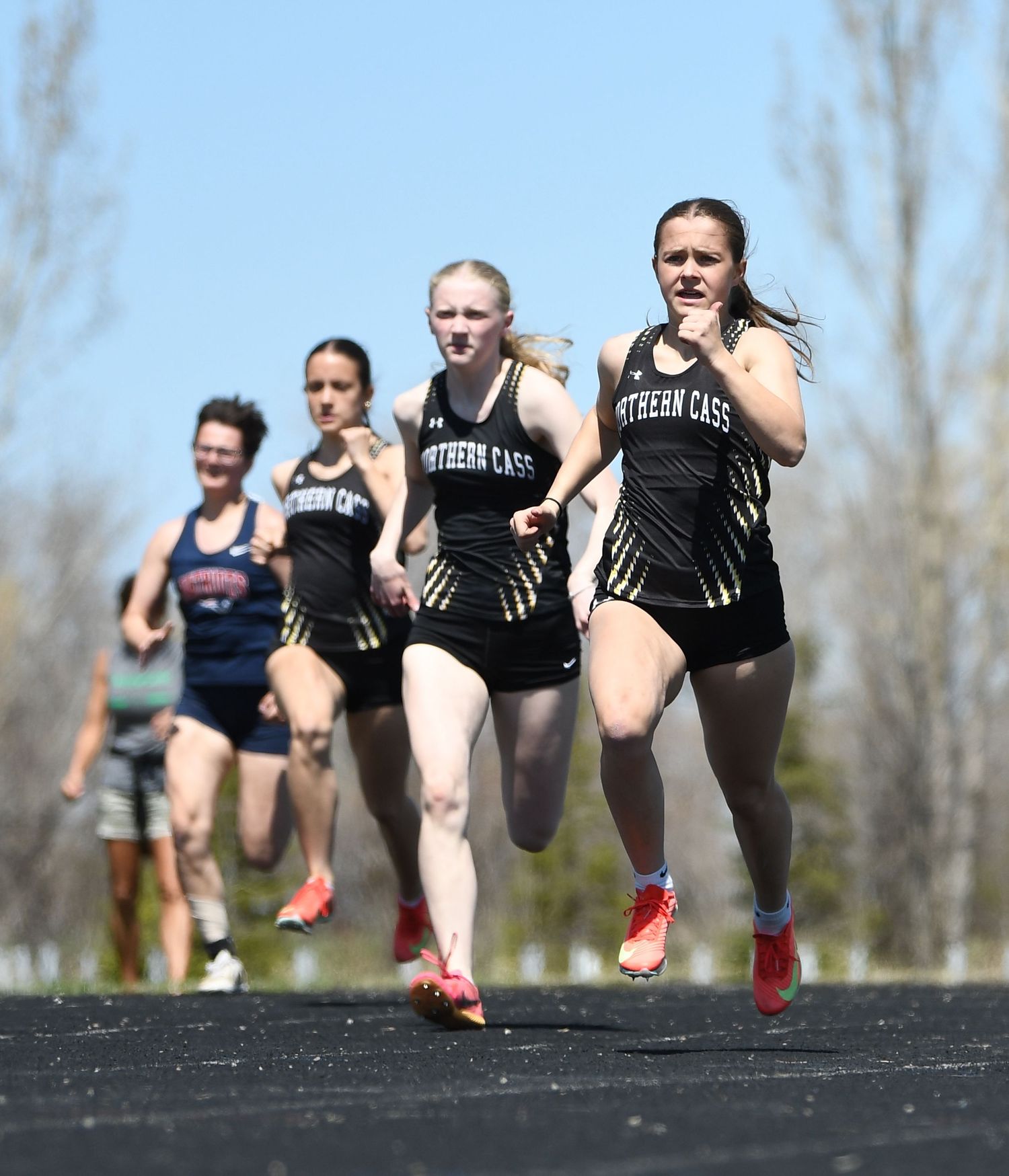 Track athletes competing in running event on outdoor track.