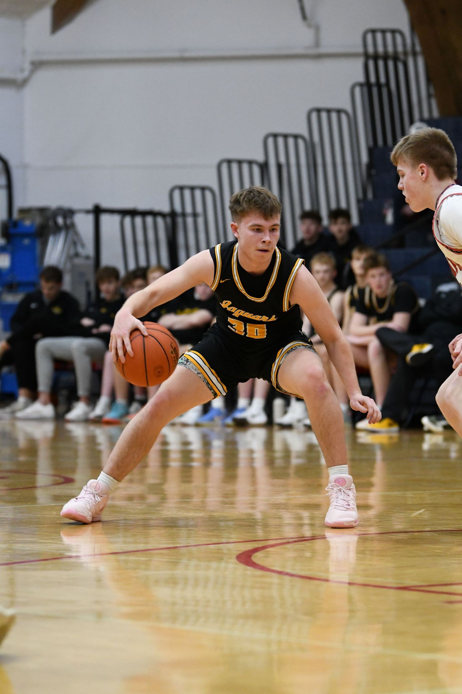 Basketball player in black uniform dribbles low while making offensive move.