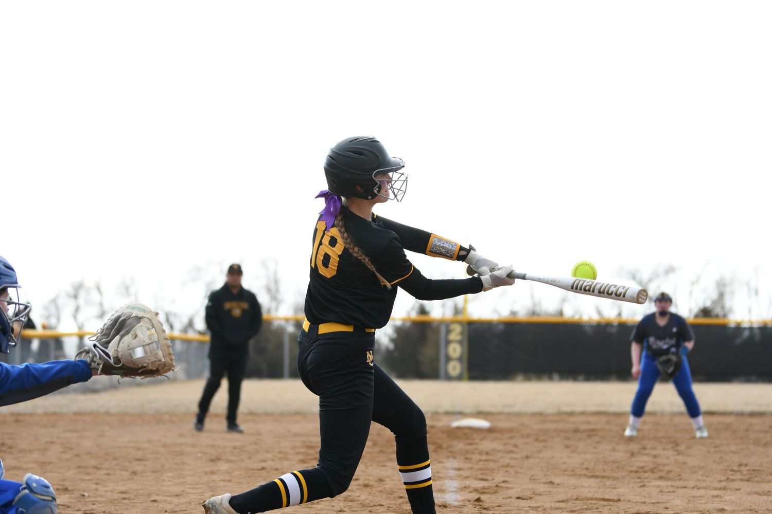 Softball player in black uniform making defensive play on dirt infield.
