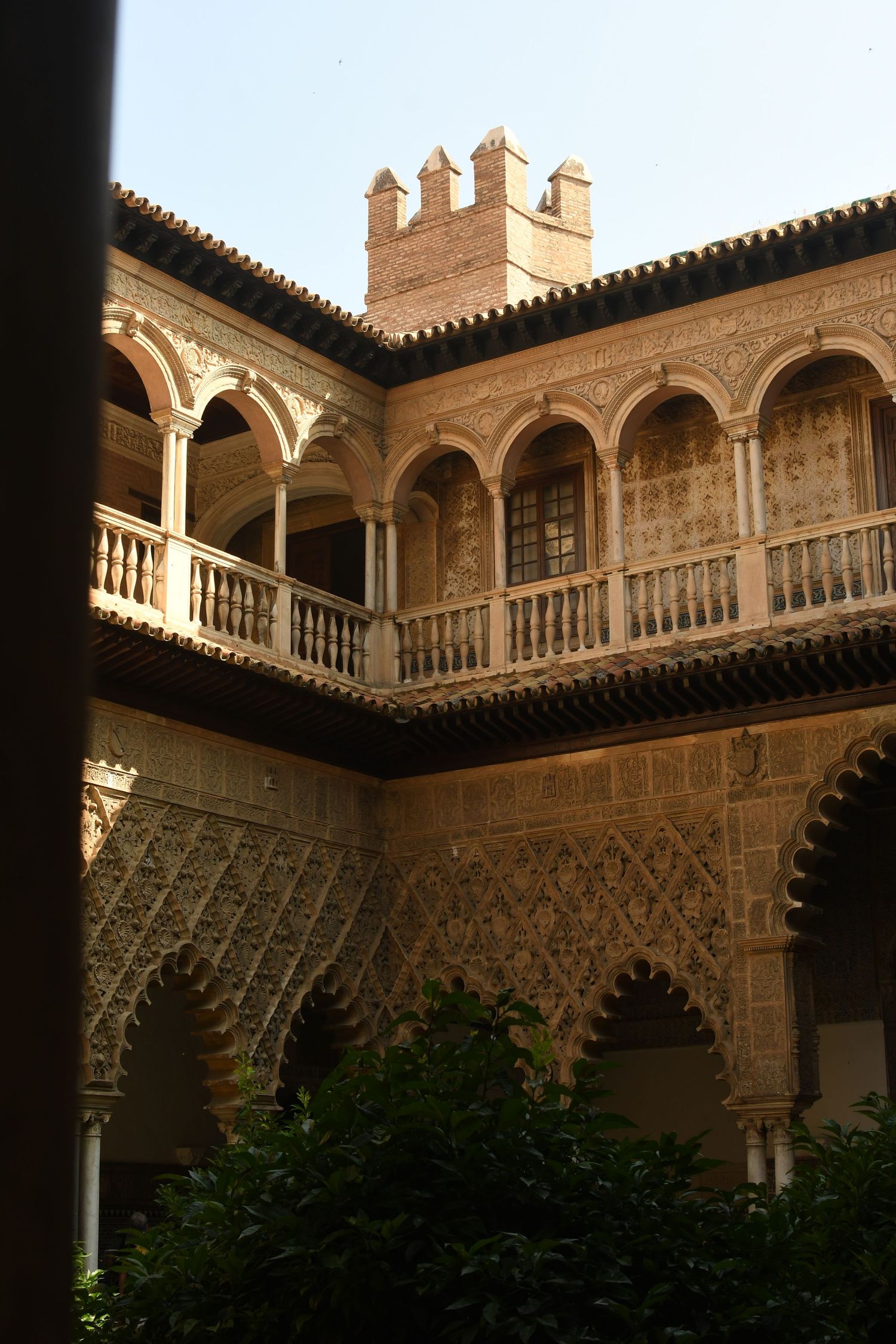 Historic courtyard with decorated Moorish arches and balconies in warm sunlight.