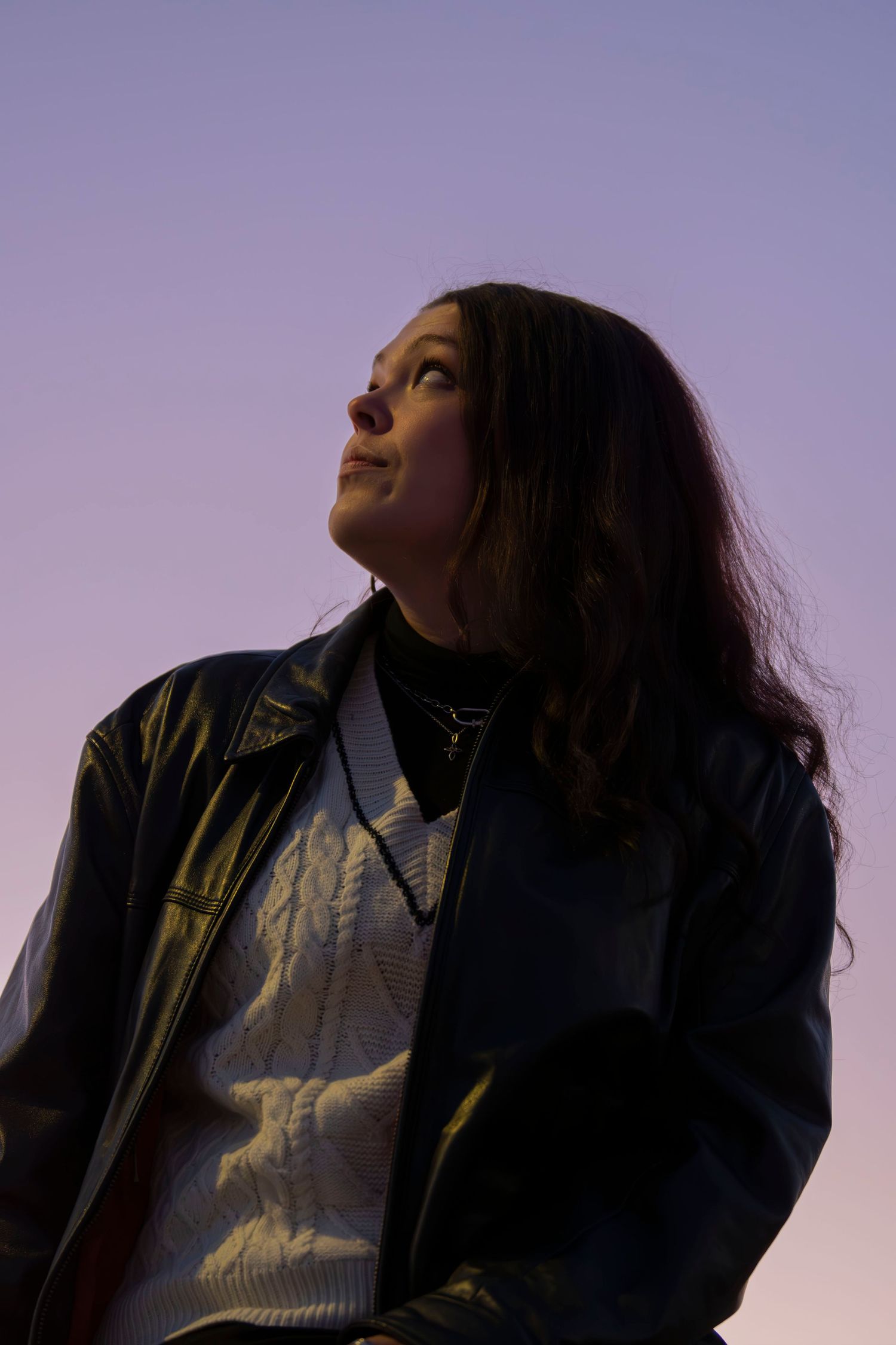 Person in a denim jacket gazes upward against a dusky purple sky in a series of artistic portrait shots.