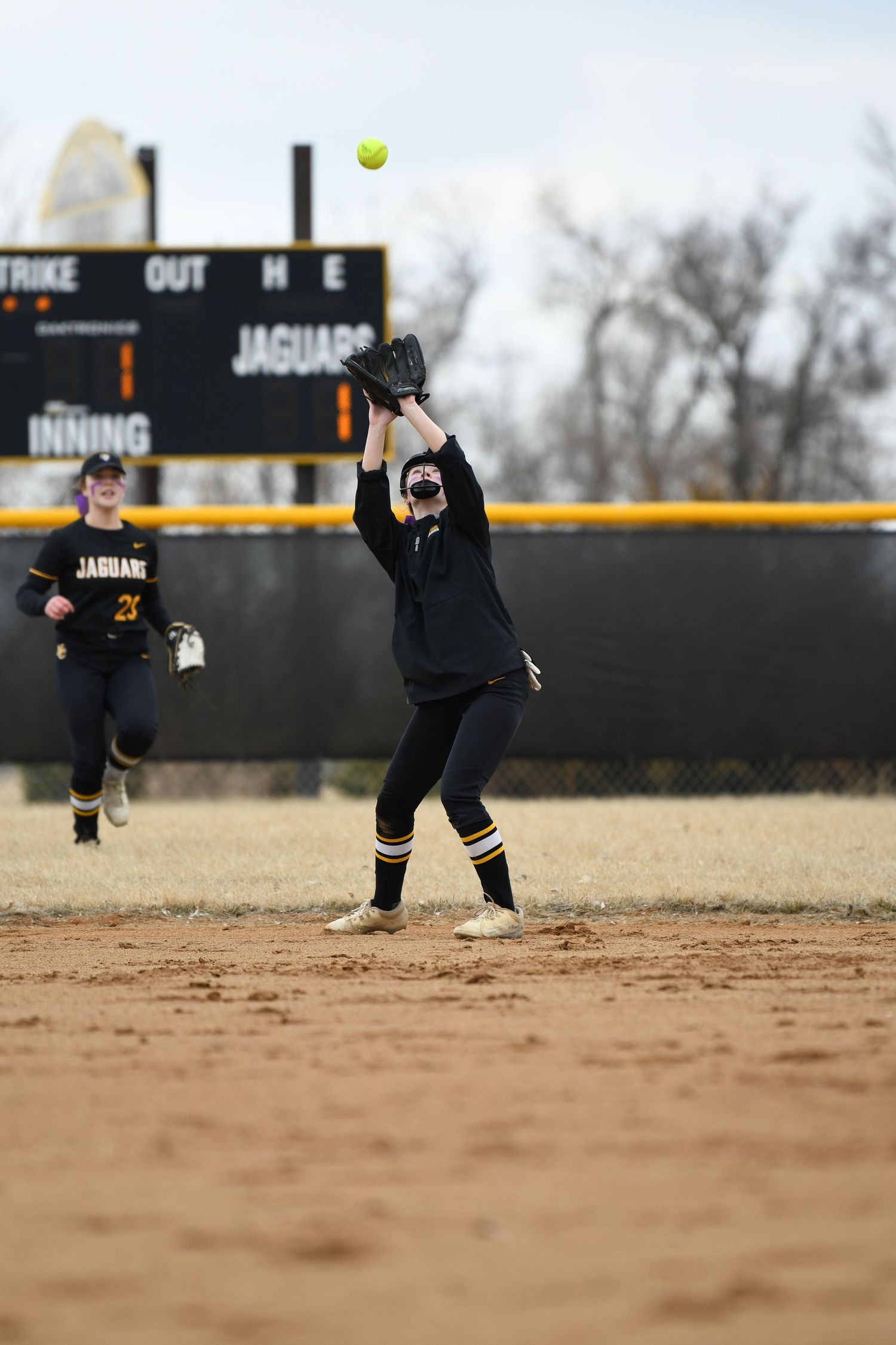Action sequence of softball player fielding ground ball on dirt infield.