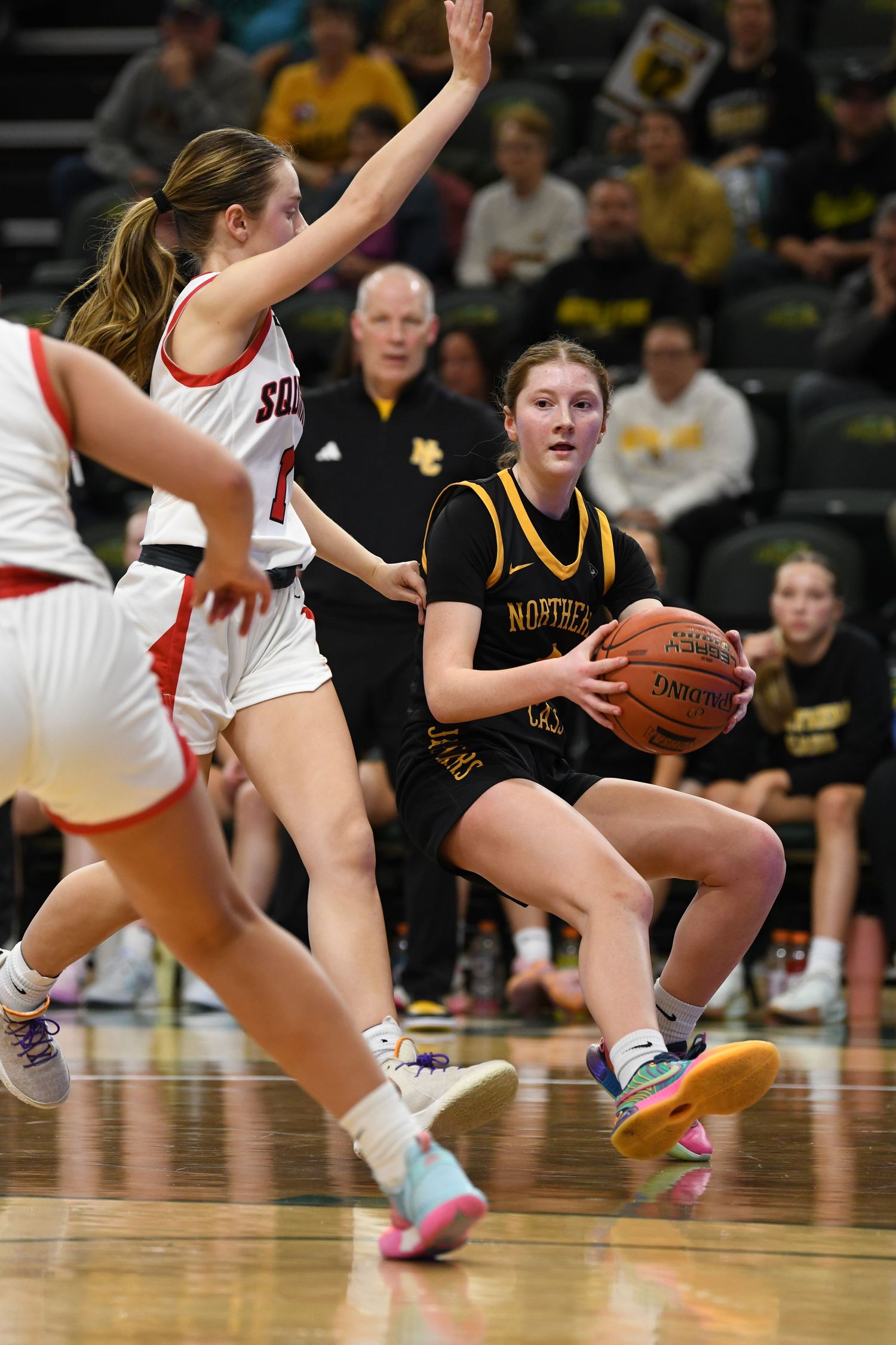 Basketball player in black jersey looks to pass while being defended during game.