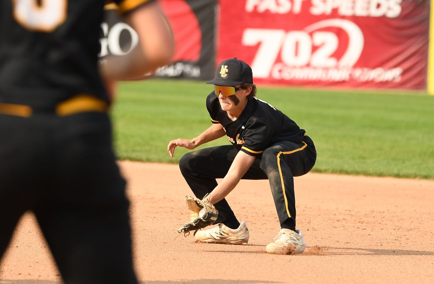 Baseball players demonstrating sliding techniques with advertisement banners visible in background.
