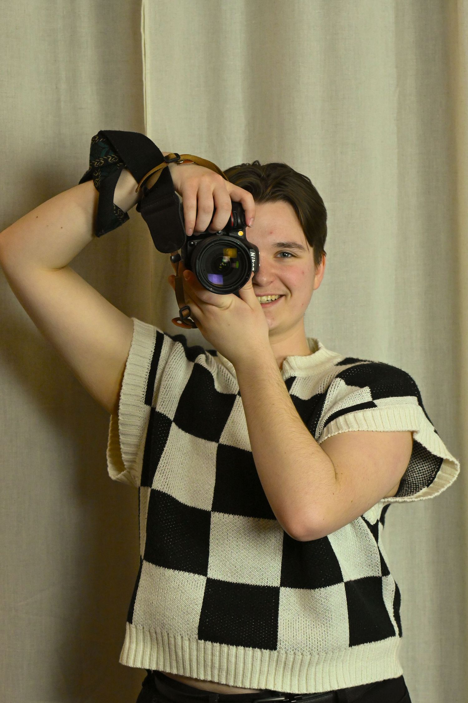 Photographer wearing black and white checkered sweater taking photos in an animated sequence.