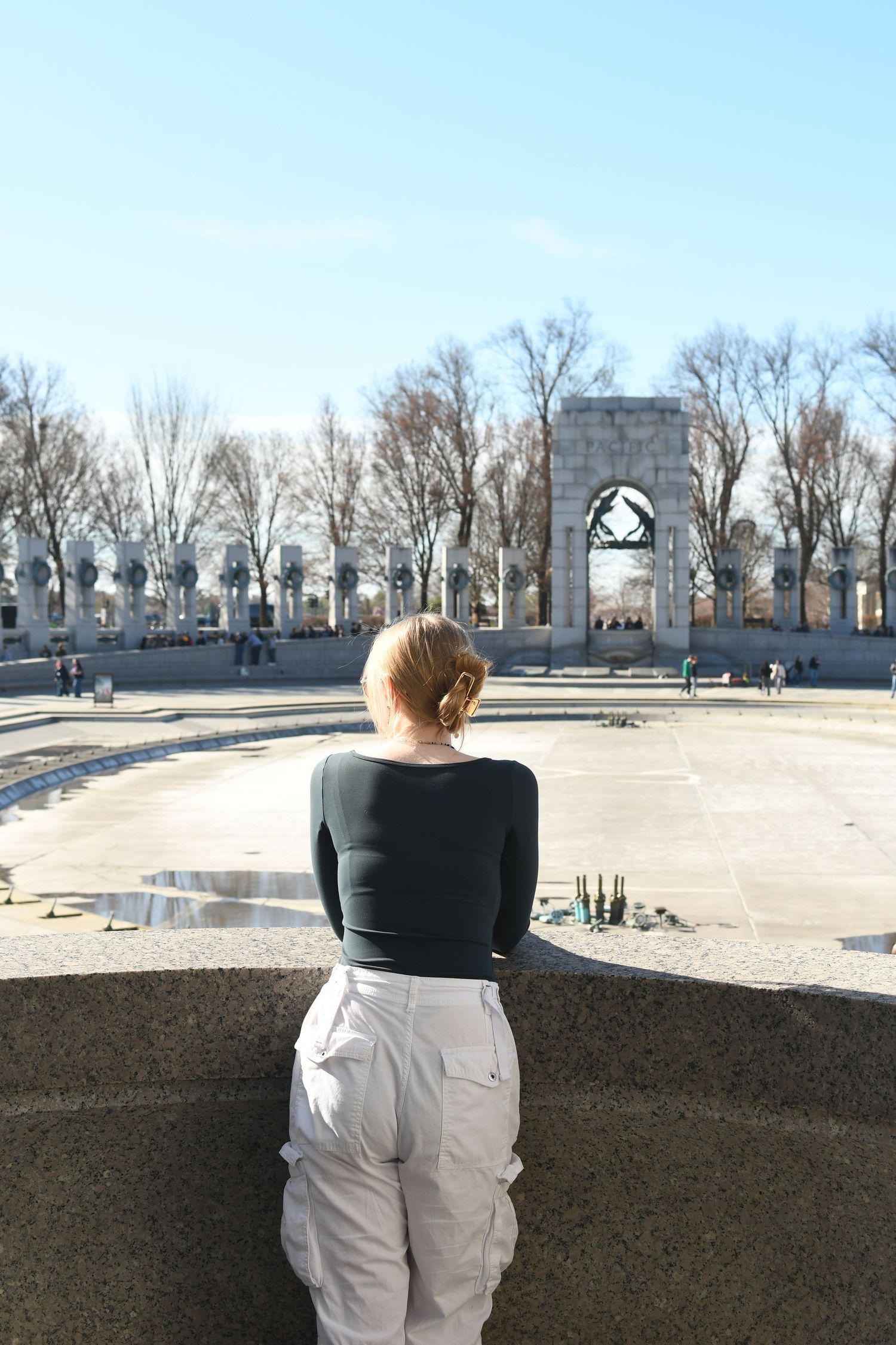 Back view of person looking at stone archway monument on winter day.