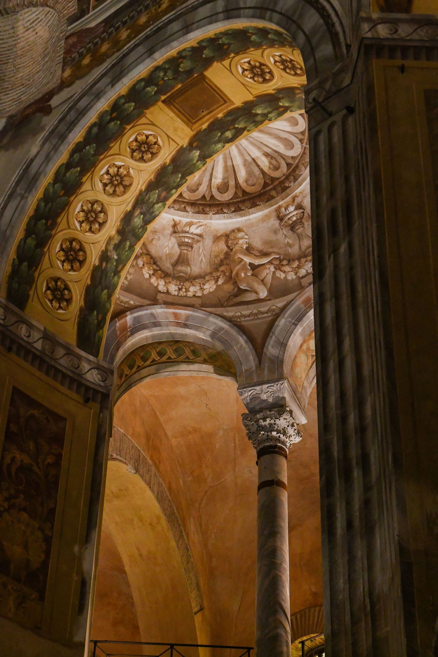 Ornate architectural details of arched ceiling with painted frescoes and stone columns.