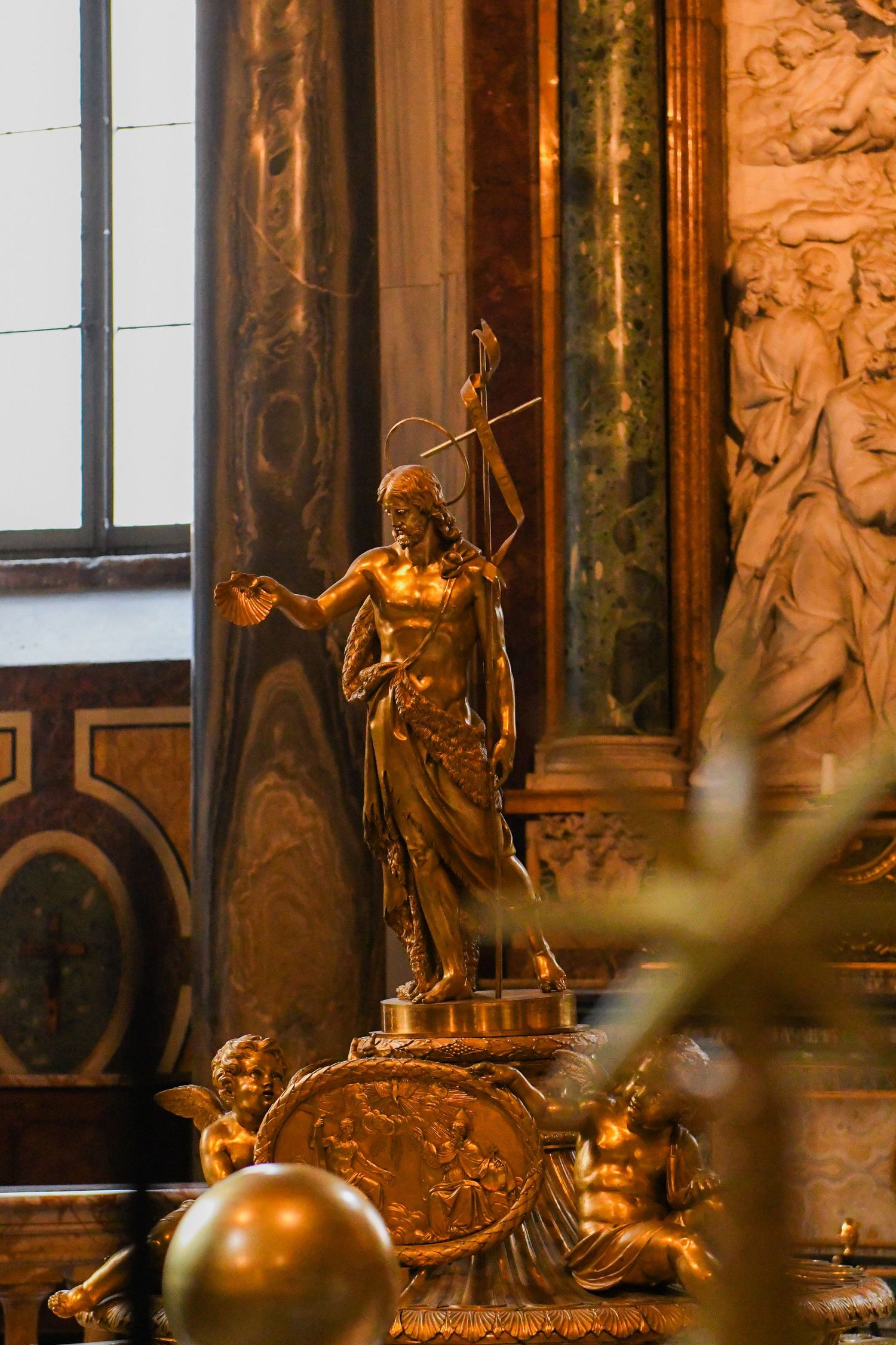 Golden baroque sculptures and ornaments illuminated in warm light against dark interior walls.