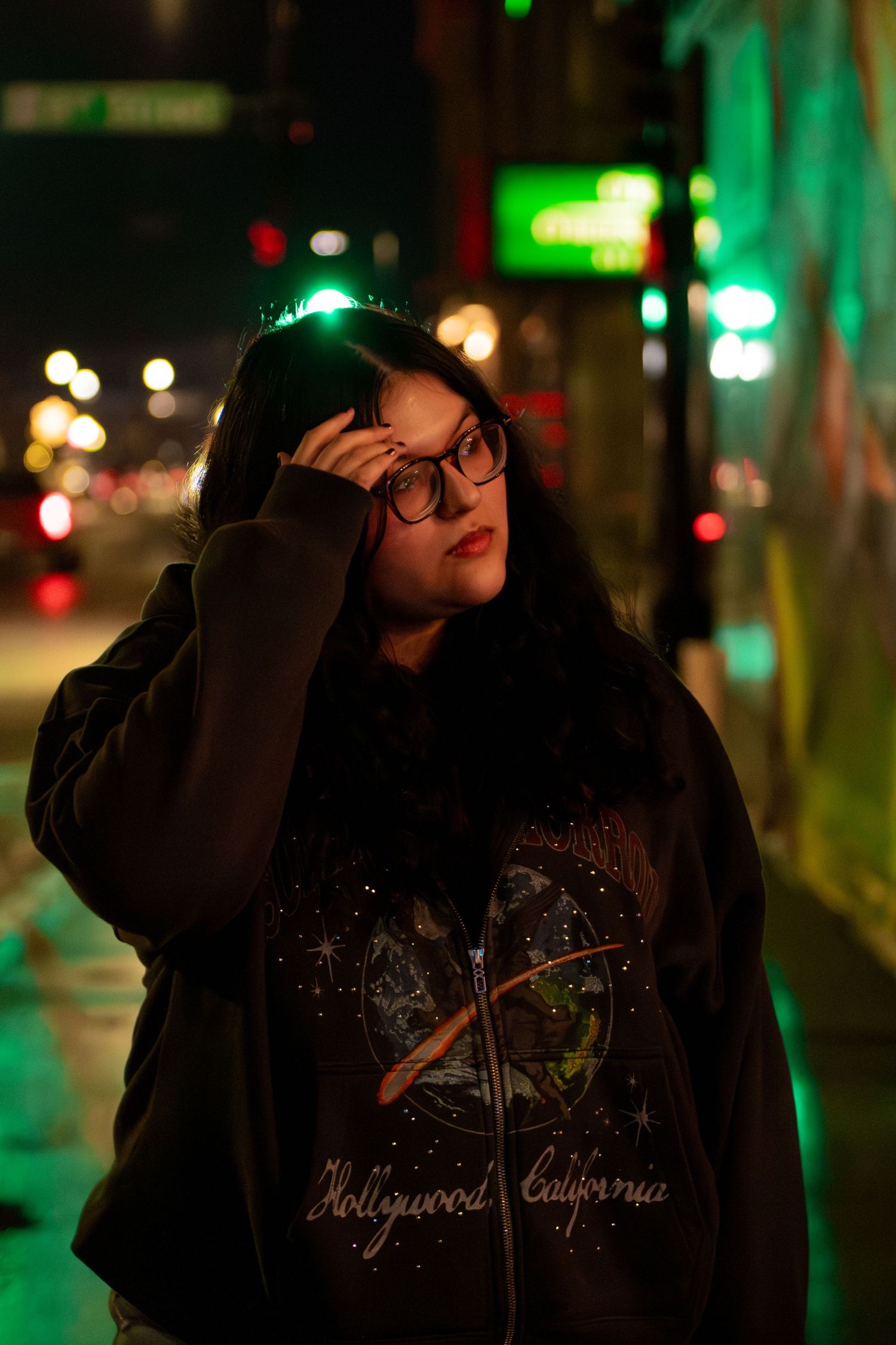 Moody nighttime street photography with neon lights and bokeh illuminating a dark scene.