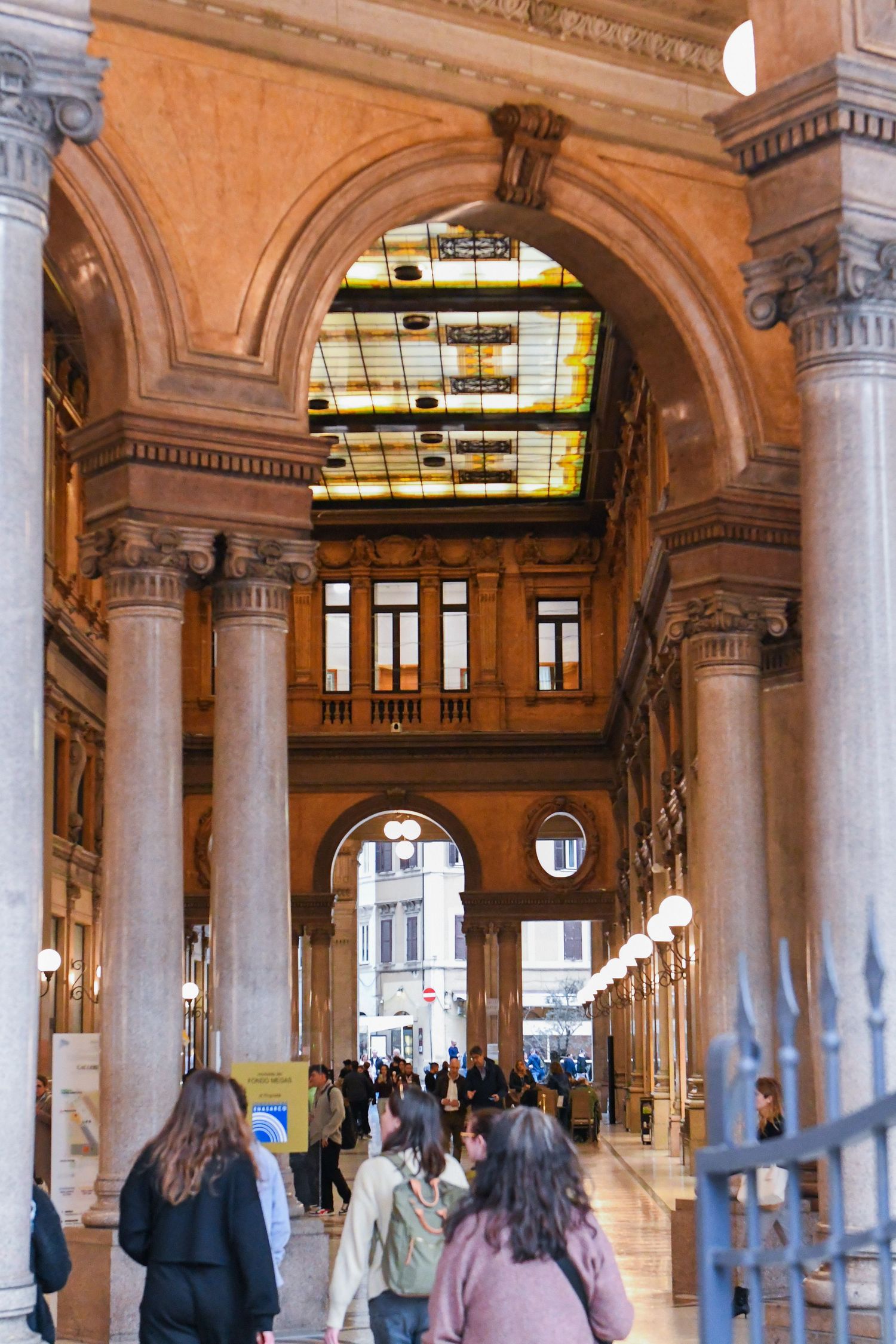 Elegant colonnade with marble pillars and arched ceilings in a historic Italian building.