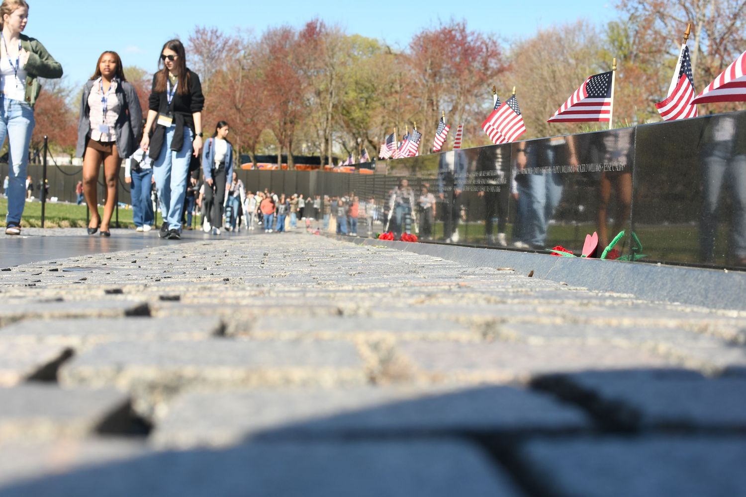 People walk along a cobblestone path lined with American flags.