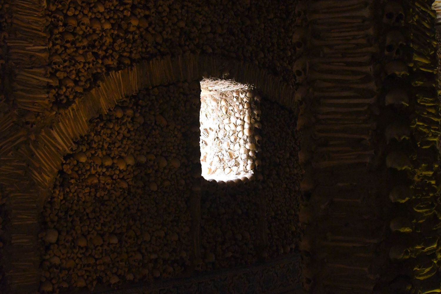 Dark stone tunnel or passageway with dramatic lighting and textured brick walls.