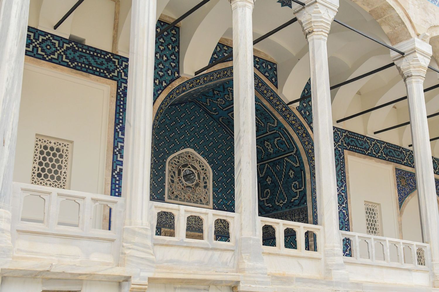 White marble columns and arches in a historic mosque's interior courtyard.