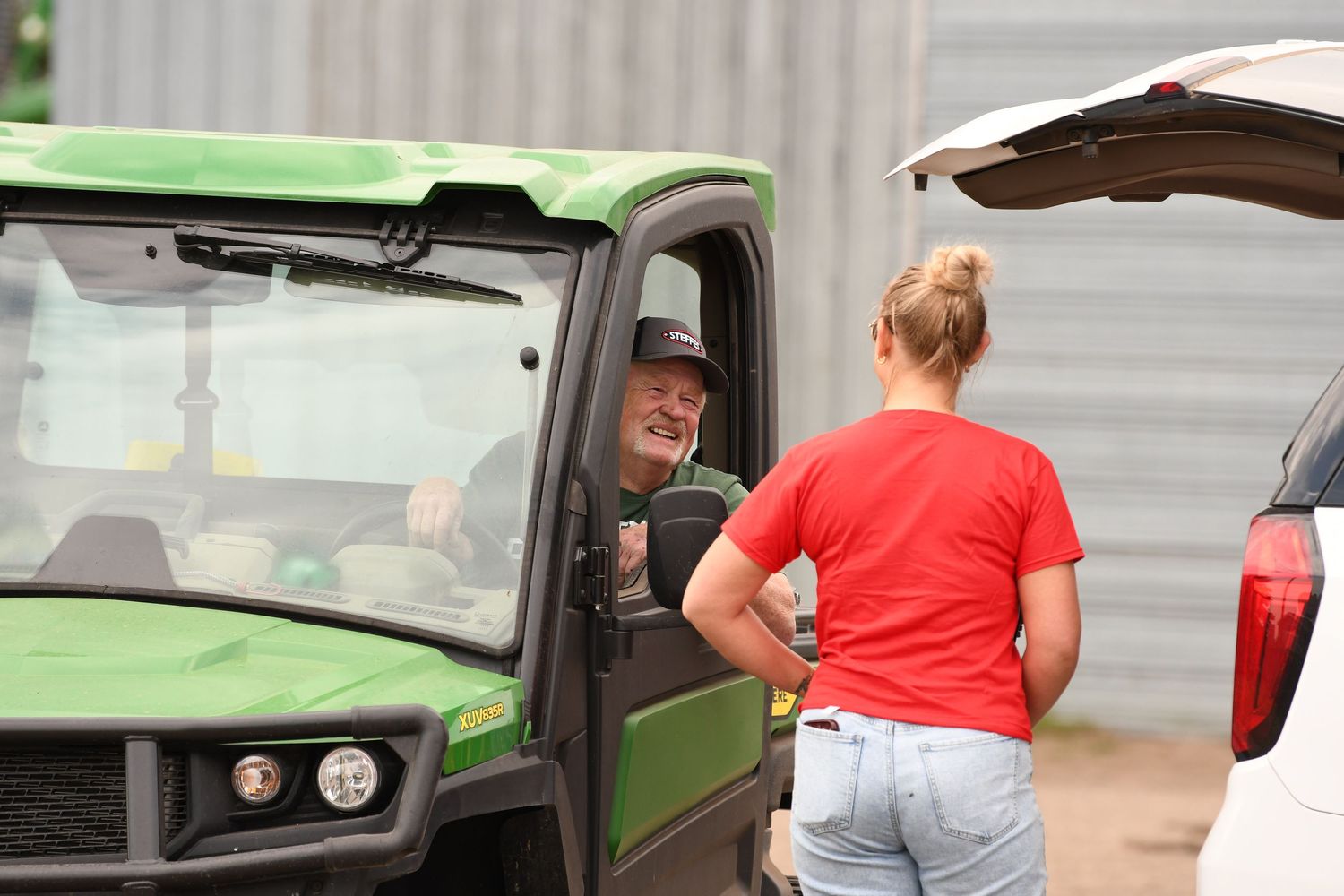 Side view of a person alongside a commercial vehicle in an agricultural setting.