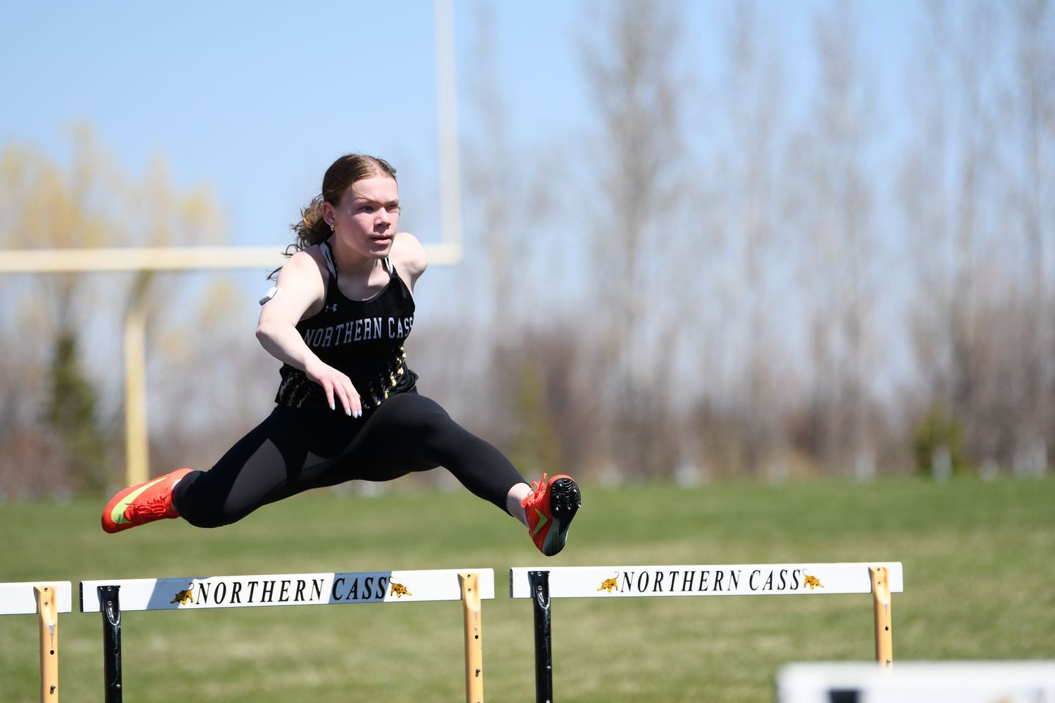 Athlete jumping over hurdle during track meet competition.
