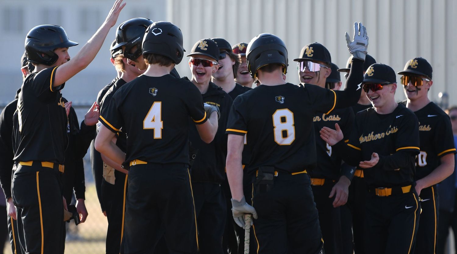 Baseball team in black and gold uniforms celebrates together during game.