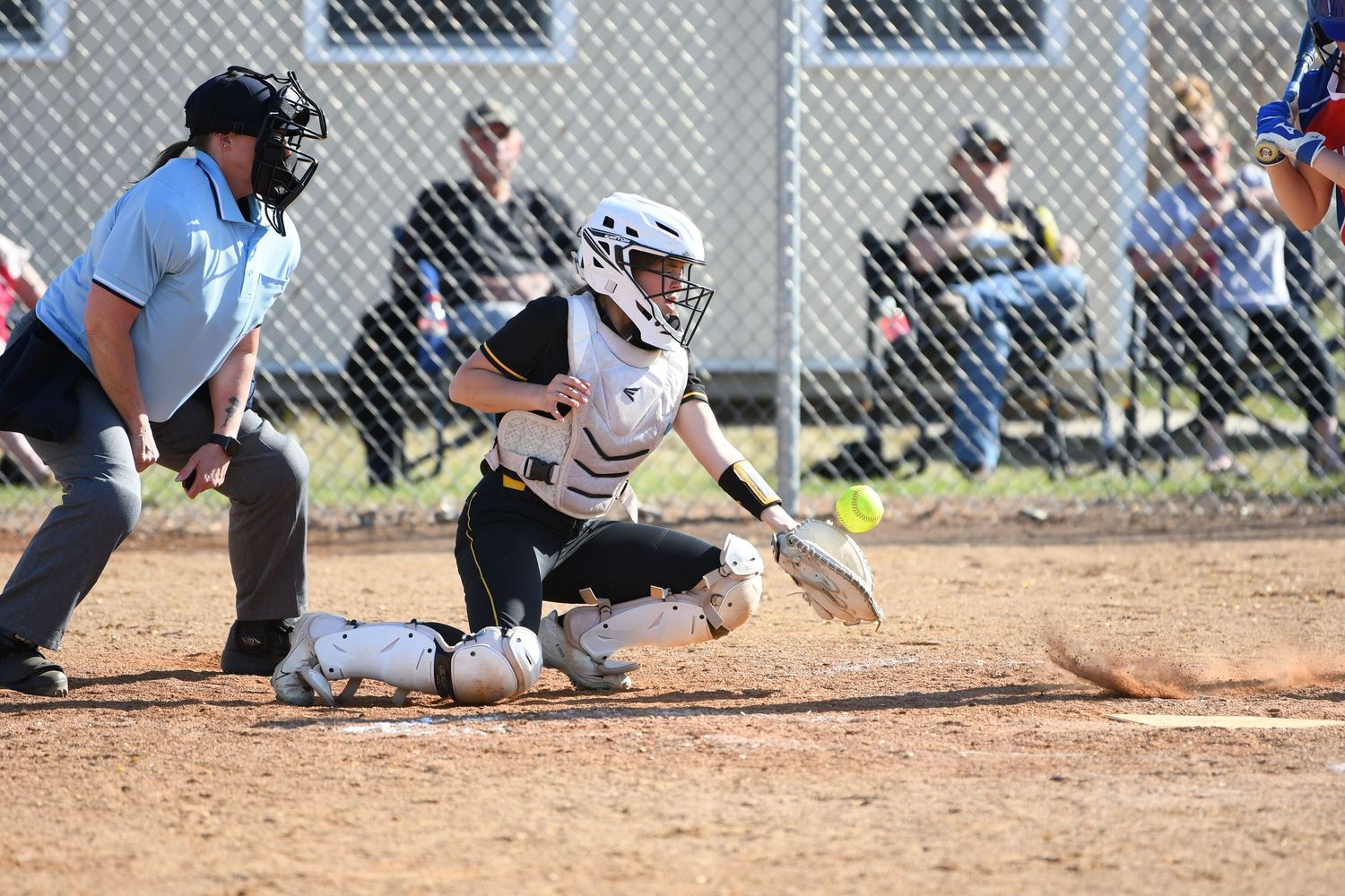 Softball player sliding into base during competitive game action.