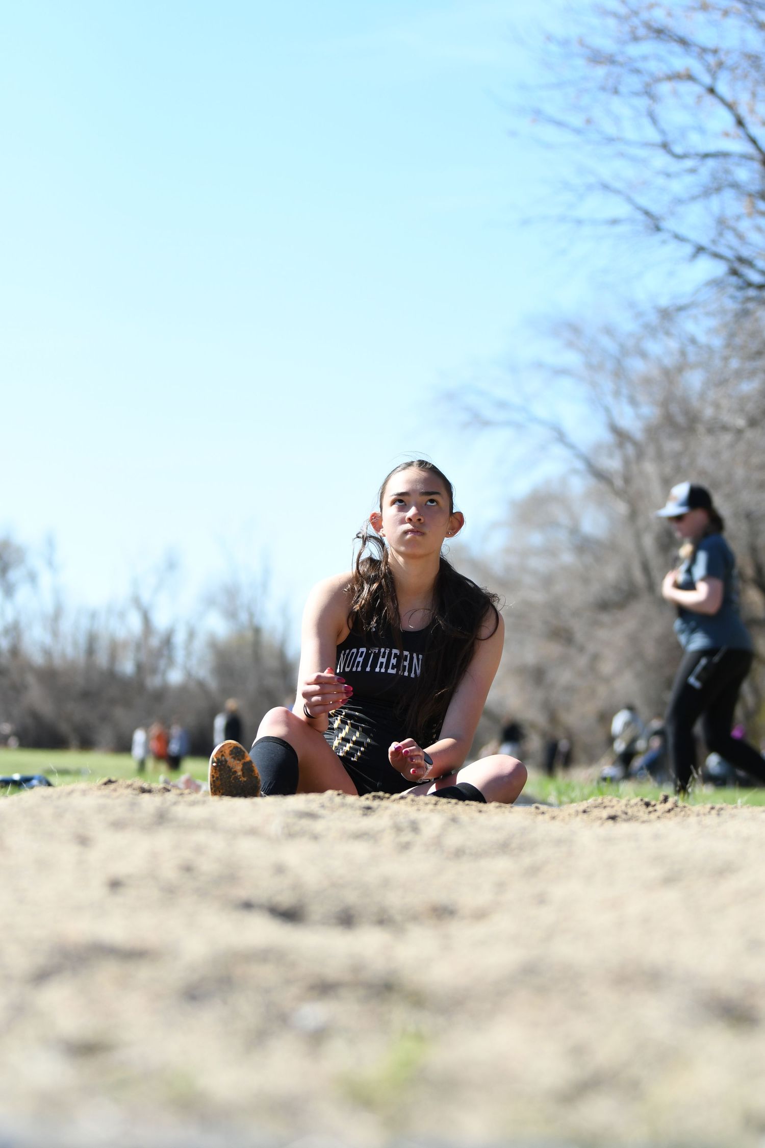 Athlete in black uniform preparing for sand pit landing during field event.
