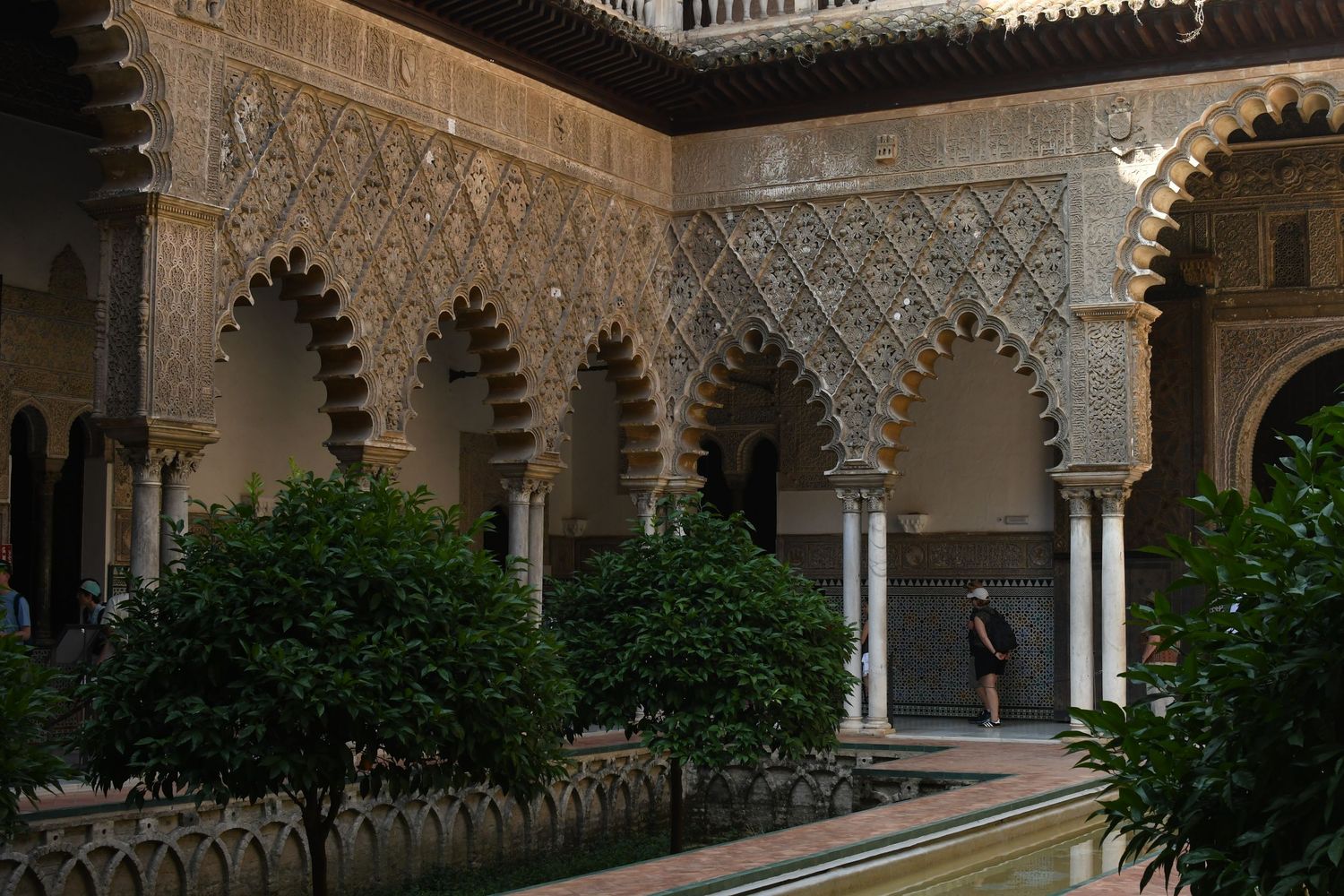 Intricate Moorish architecture with horseshoe arches and geometric patterns in a courtyard garden.