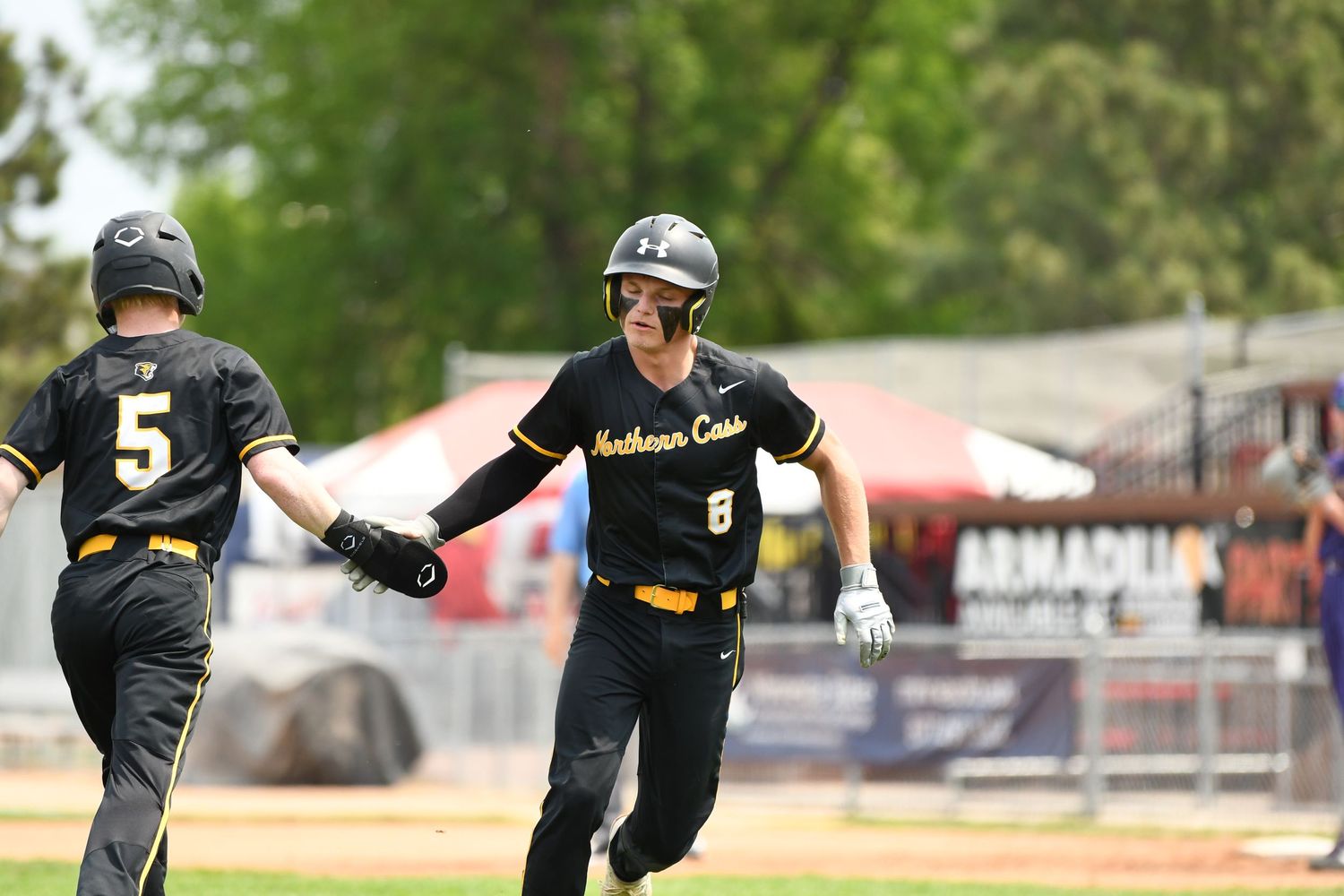 Two baseball players in black uniforms celebrate together on the field during a game.
