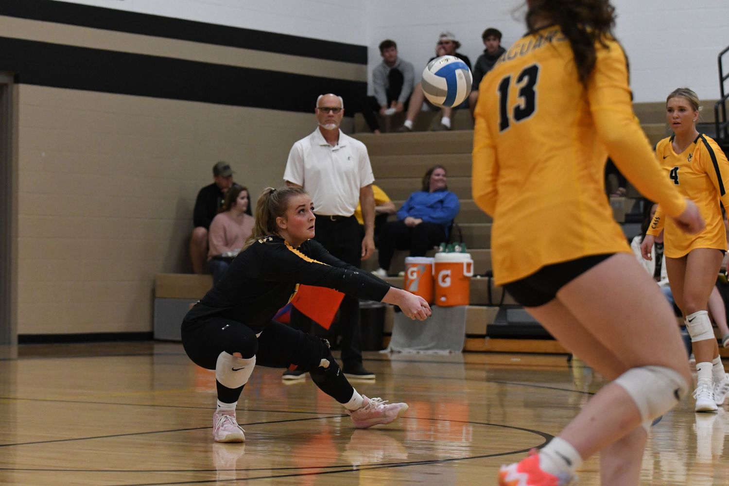 Player in black uniform dives for a low ball during intense volleyball play.