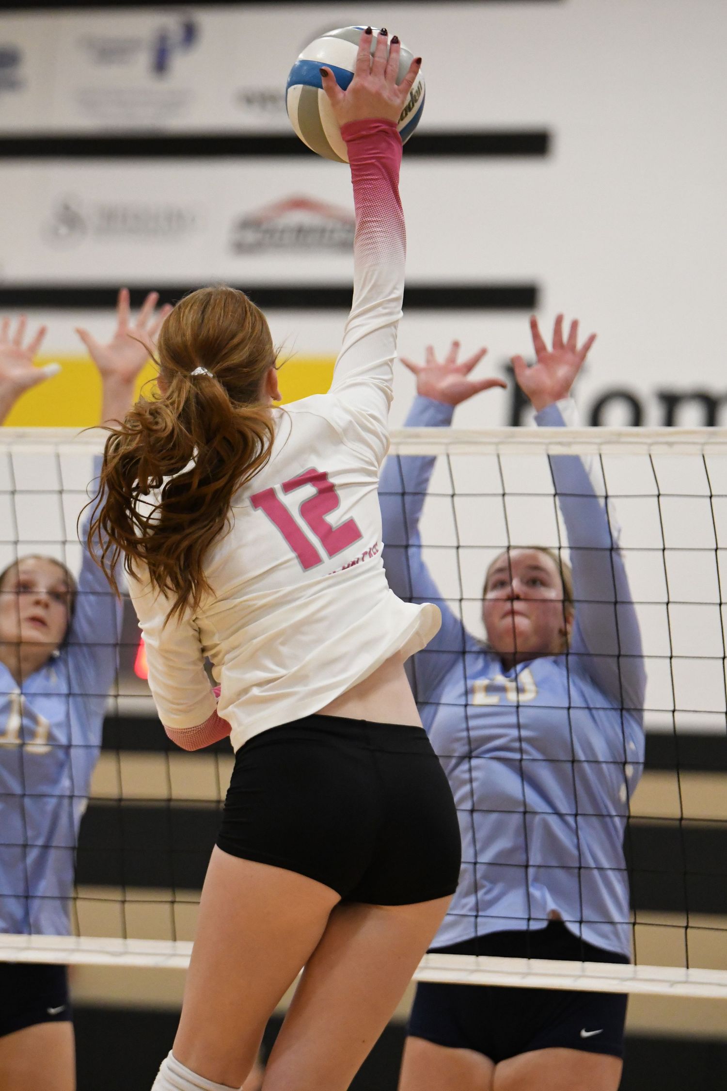 Team of volleyball players jumping at the net during defensive play.