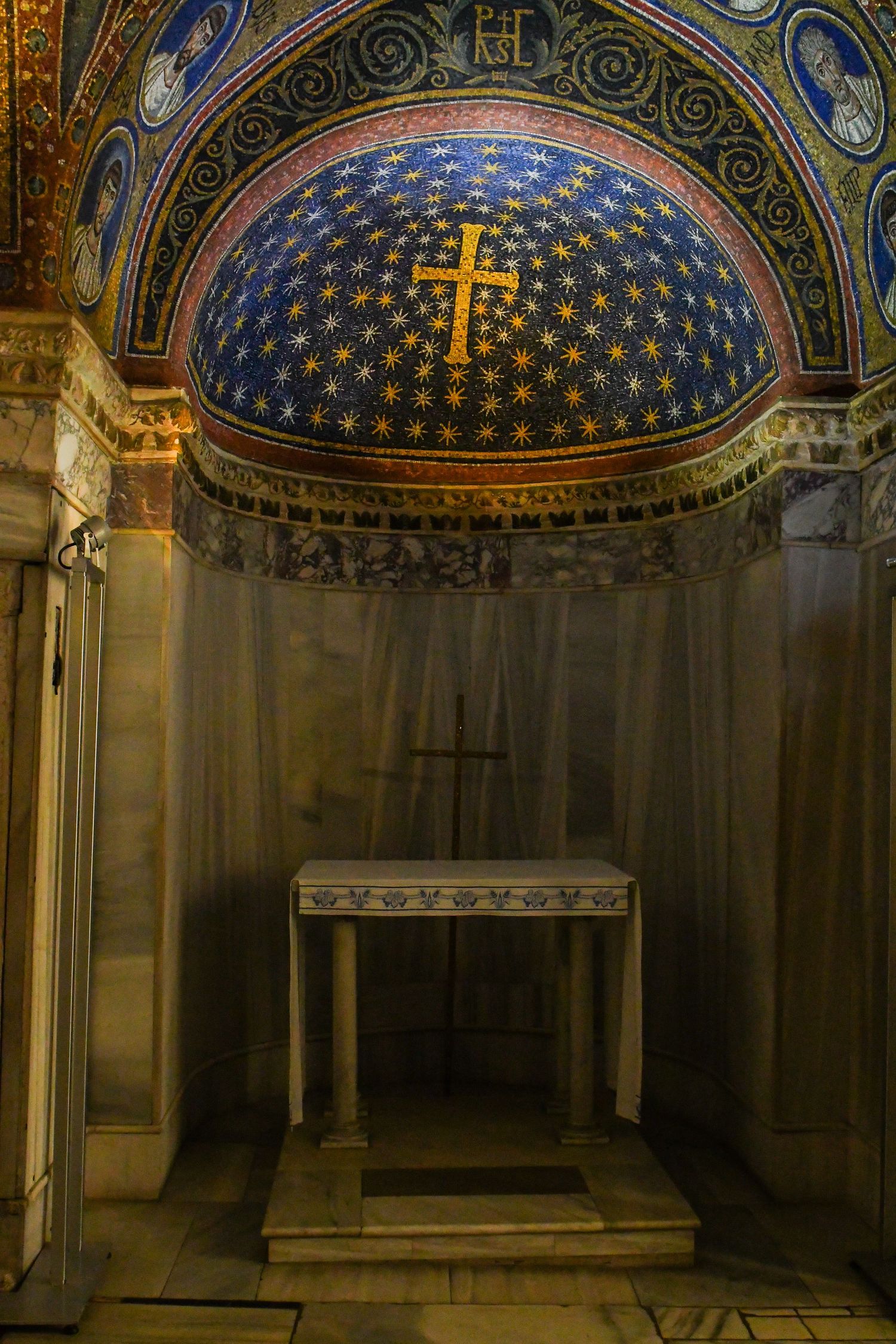 Ancient church interior with blue and gold mosaic ceiling featuring religious symbols and crosses.