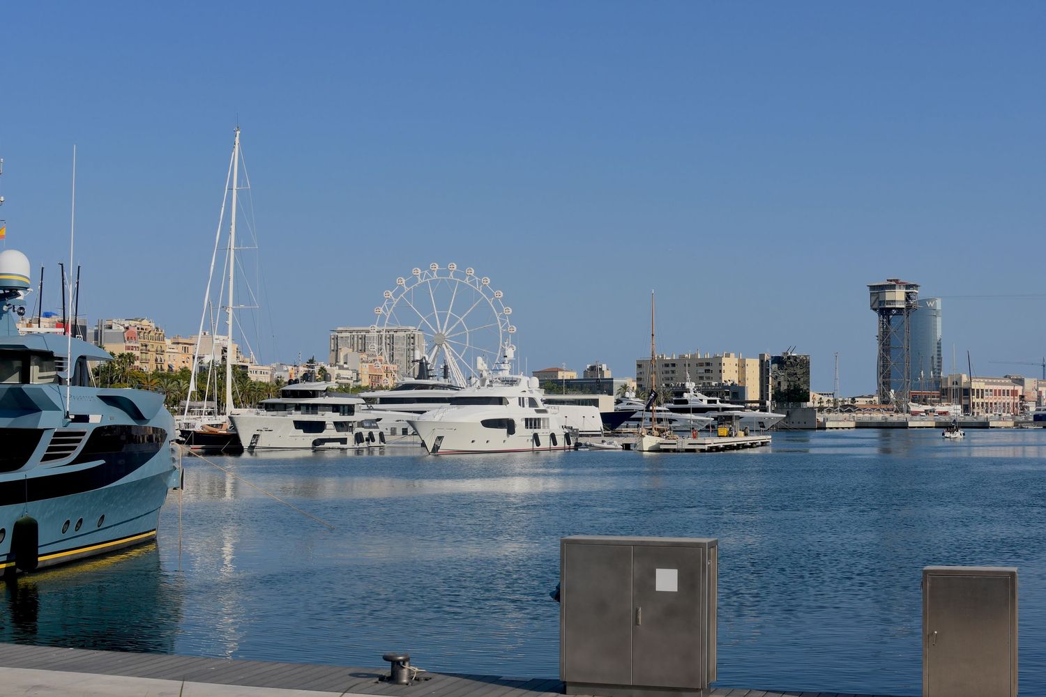 Marina with luxury yachts and boats docked at sunset with city skyline in background.