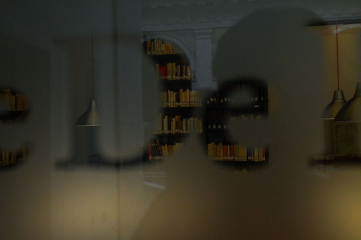 Dark interior view of a library or study space with bookshelves visible in low lighting.