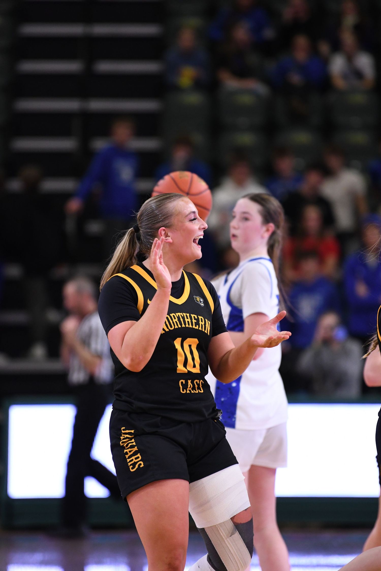 Basketball player in black uniform dribbles ball during intense game action.