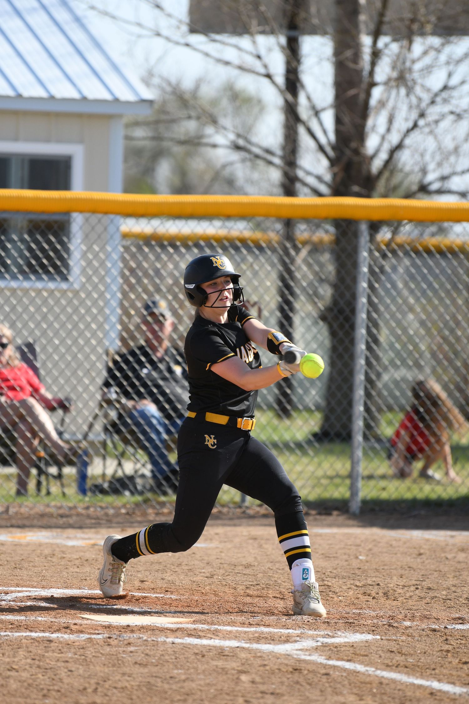 A softball player bunts the ball while positioned near home plate during a match.
